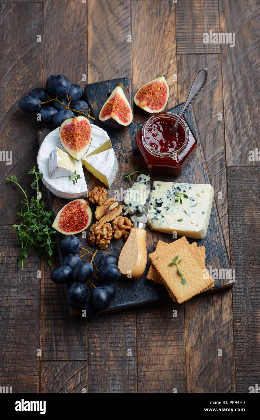 Käseplatte mit Trauben, Feigen, Cracker, Honig, Pflaumen Gelee, Thymian und Muttern, selektive konzentrieren. Stockfoto