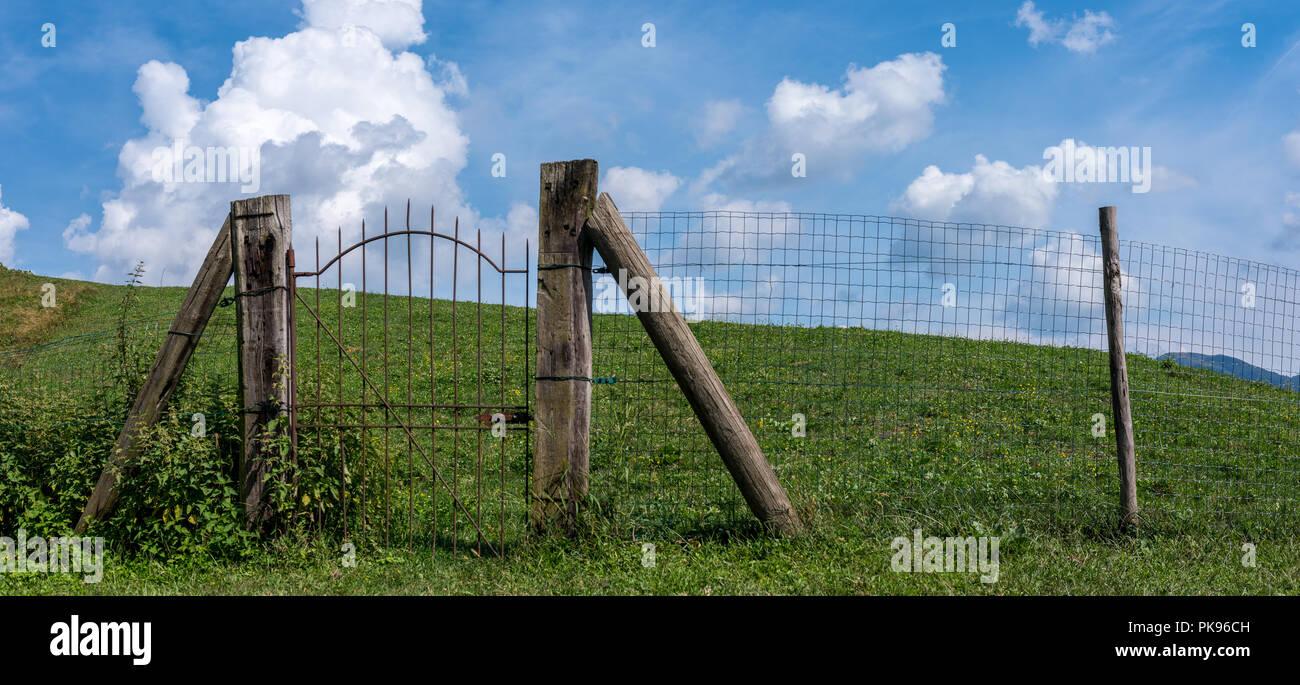Iron Gate rustikaler Zaun auf einer grünen Wiese, Pforte des Himmels auf einem Hügel Stockfoto