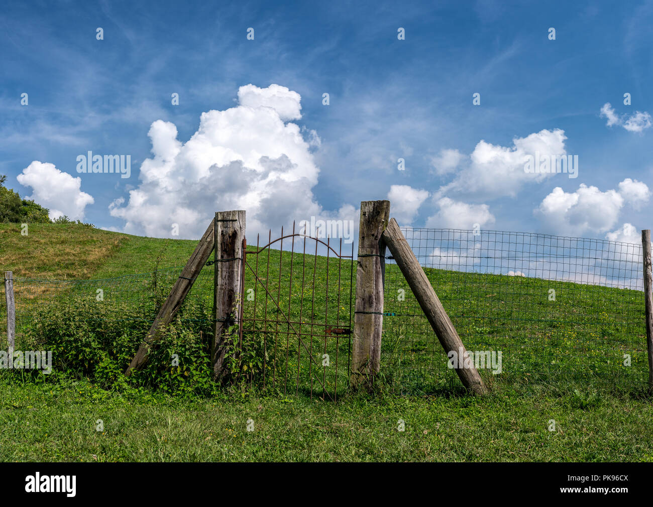 Iron Gate rustikaler Zaun auf einer grünen Wiese, Pforte des Himmels auf einem Hügel Stockfoto