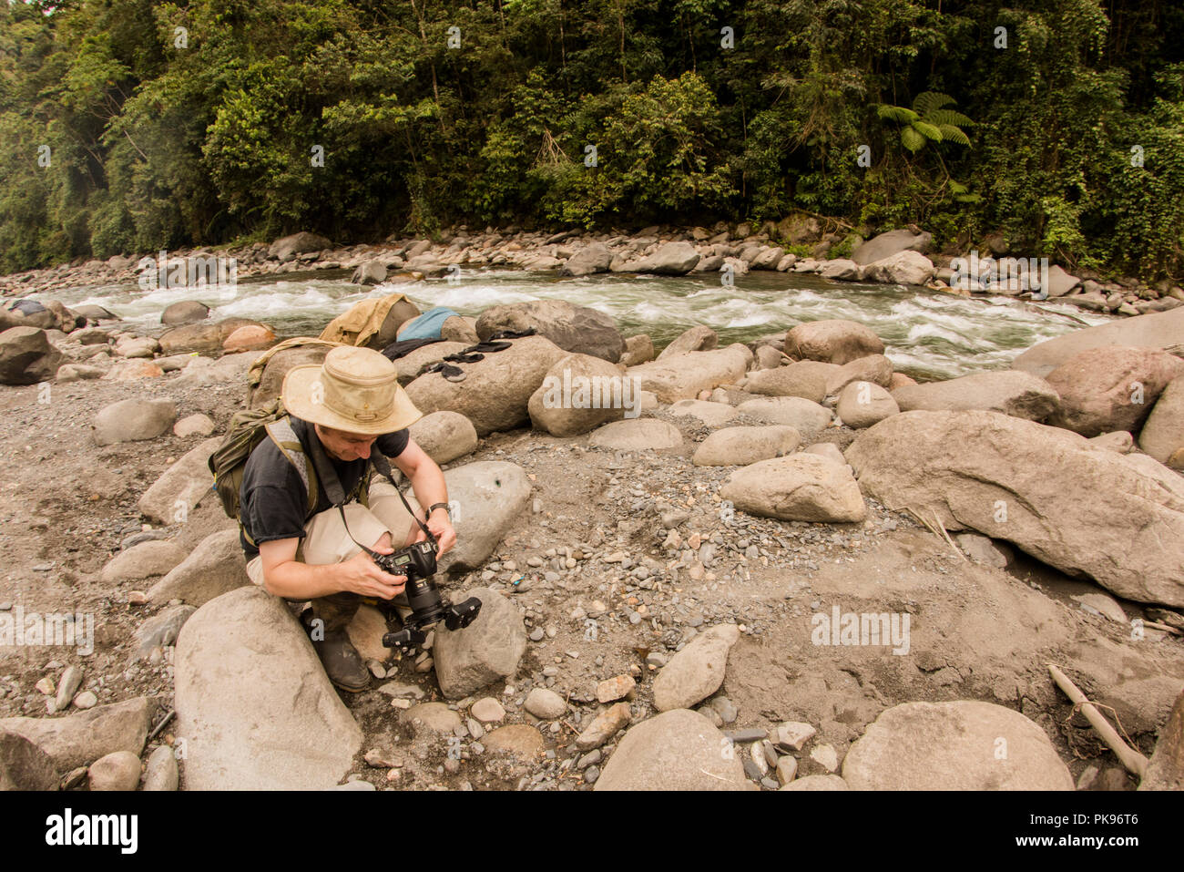 Ein Biologe an einem Fluss in der Nähe von Manu Nationalpark, Madre de Dios, Peru knien. Er ist auf der Rückseite der Kamera. Stockfoto