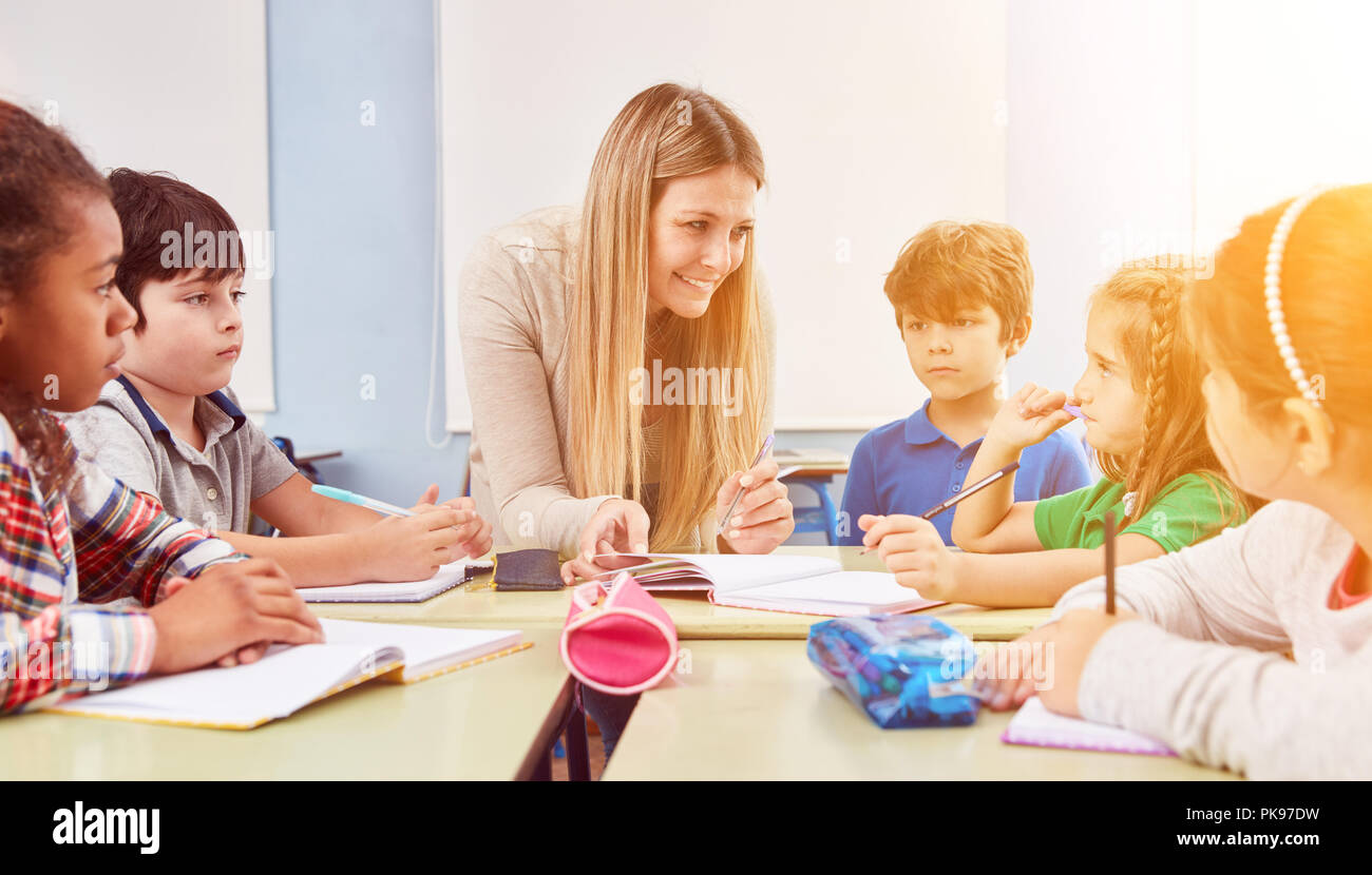 Gruppe von Kindern Hausaufgaben zusammen mit einem Lehrer in einer Ganztagsschule Stockfoto