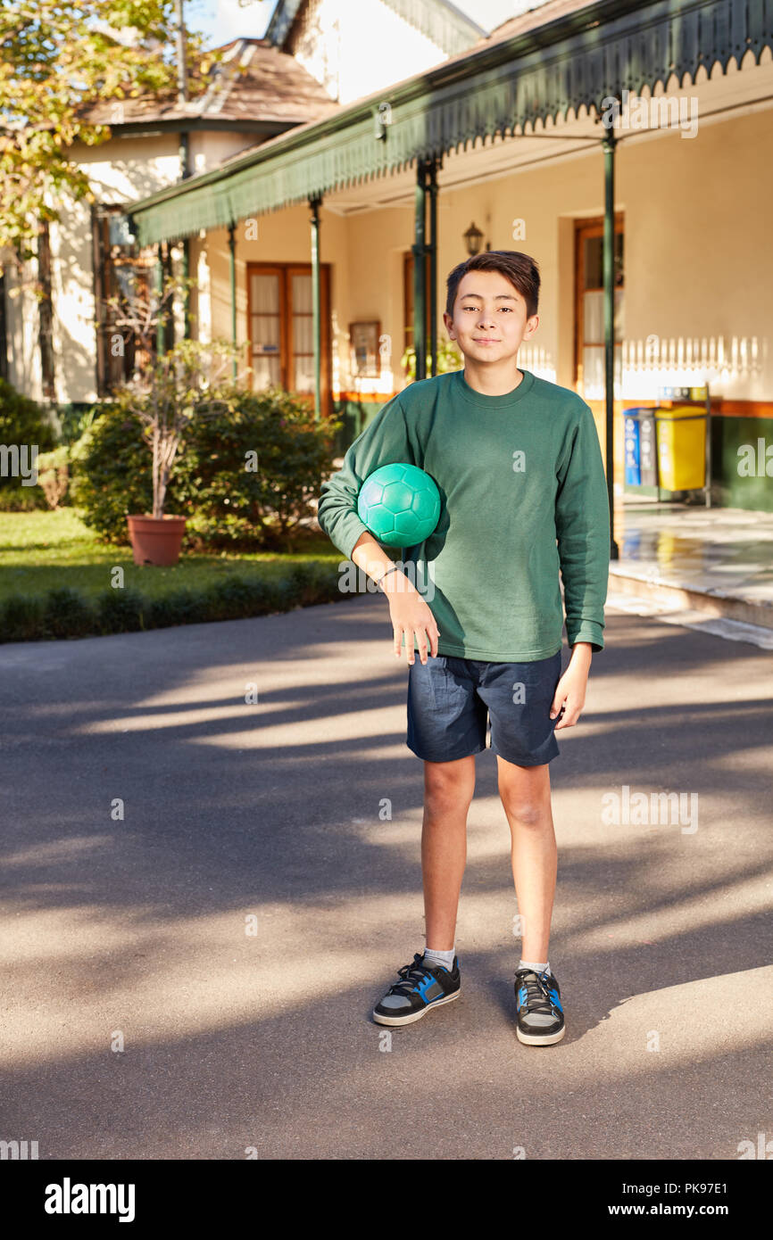 Boy steht mit einem Ball auf dem Schulhof im Summer Camp im Sommer Stockfoto