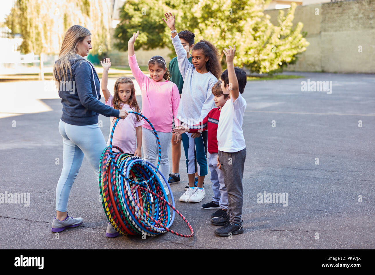 Die Frau als Lehrerin verteilt Hoops im Sportunterricht für Kinder im Summer Camp Stockfoto
