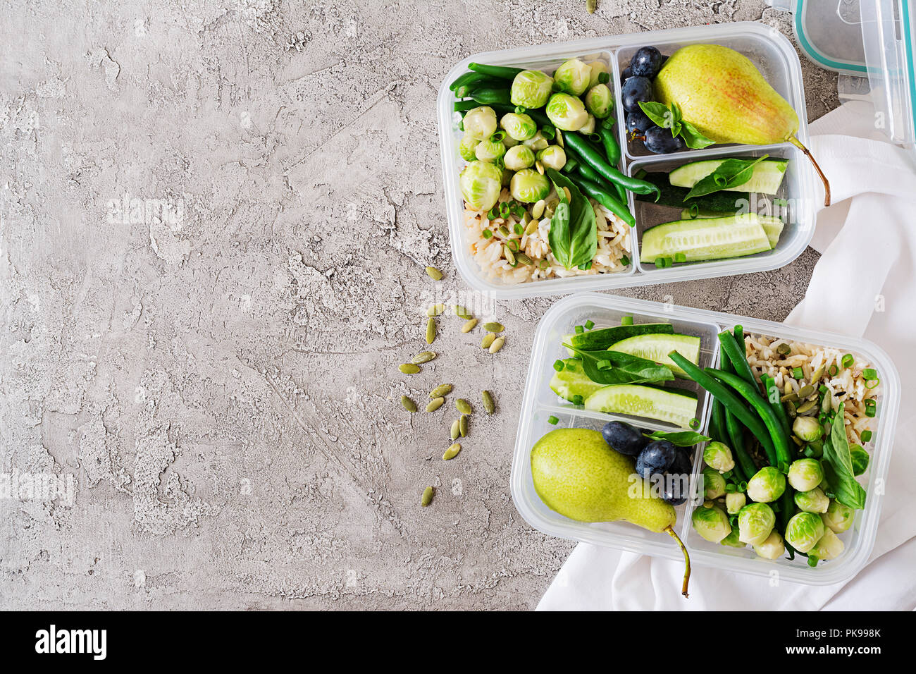 Vegane grüne Mahlzeit prep Container mit Reis, Bohnen, Rosenkohl, Gurke und Obst. Abendessen in Lunch Box. Ansicht von oben. Flach Stockfoto