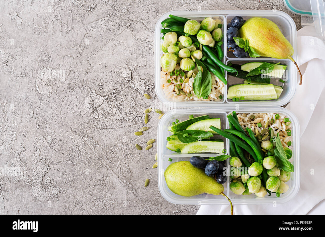 Vegane grüne Mahlzeit prep Container mit Reis, Bohnen, Rosenkohl, Gurke und Obst. Abendessen in Lunch Box. Ansicht von oben. Flach Stockfoto