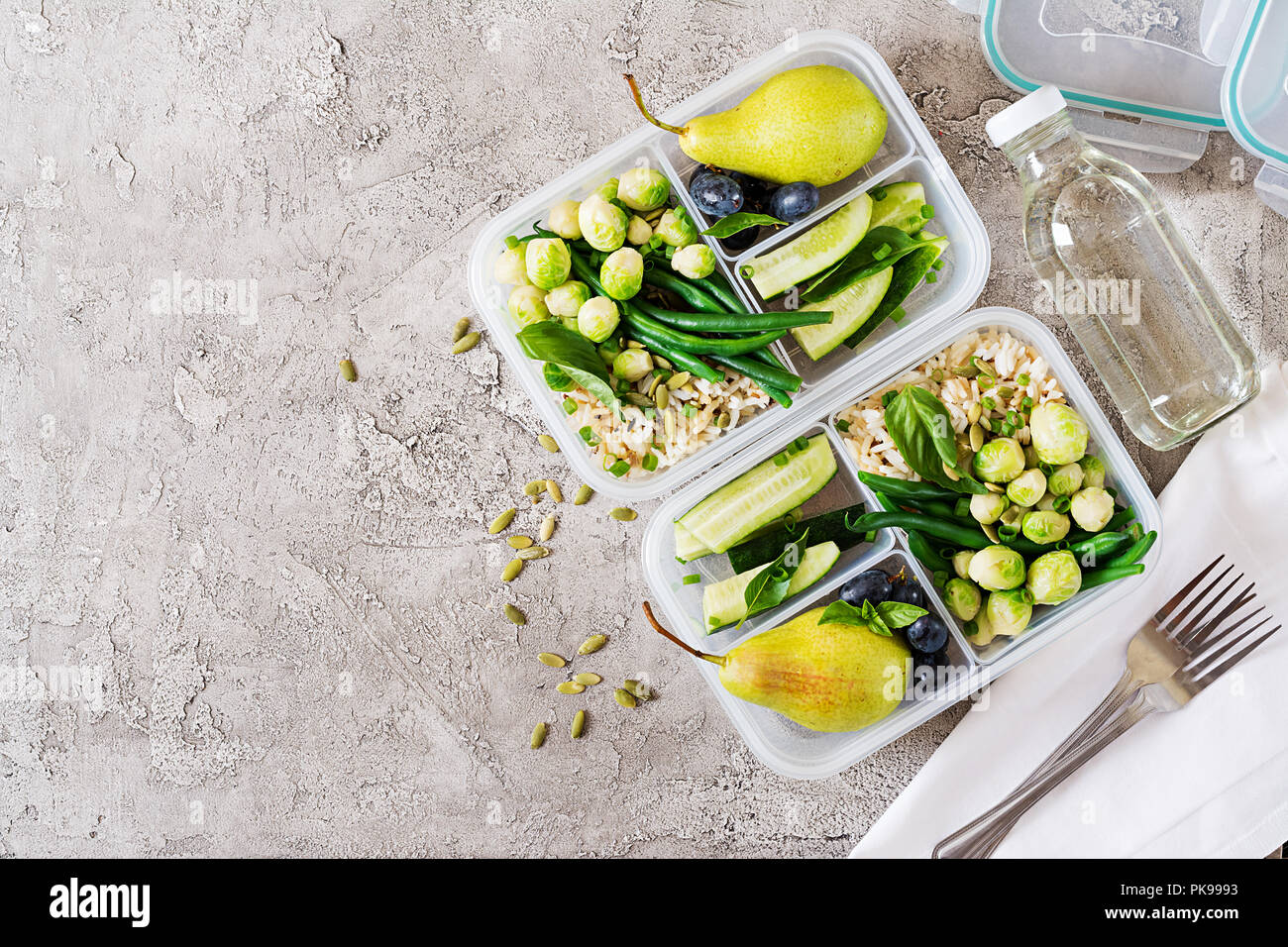 Vegane grüne Mahlzeit prep Container mit Reis, Bohnen, Rosenkohl, Gurke und Obst. Abendessen in Lunch Box. Ansicht von oben. Flach Stockfoto