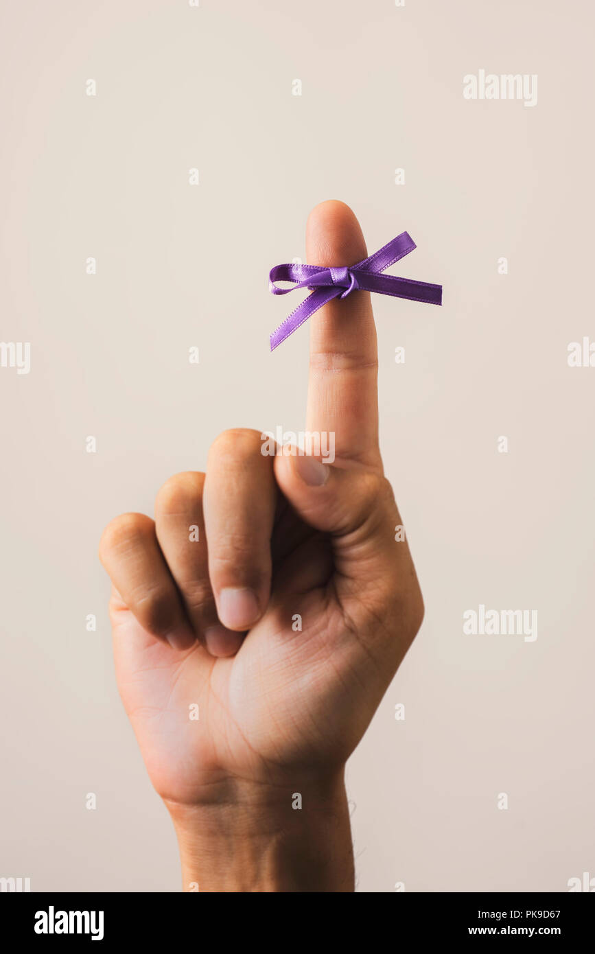 Mann mit einer lila Schleife zu seinen Zeigefinger gebunden, für die Welt alzheimers Tag, auf einem weißen Hintergrund Stockfoto