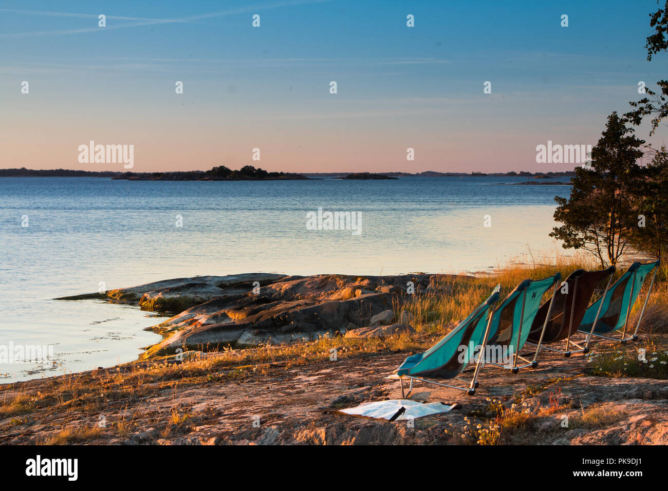 Vier leere Lager liegen in einer Linie mit Blick auf den Sonnenuntergang über dem Meer in Schwedens St Anna Archipel. Stockfoto