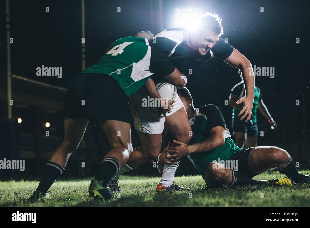 Starker Rugby-Spieler, der versucht, dem gegnerischen Team zu entkommen. Spieler des rugby-Teams treten im Spiel unter Licht an. Stockfoto