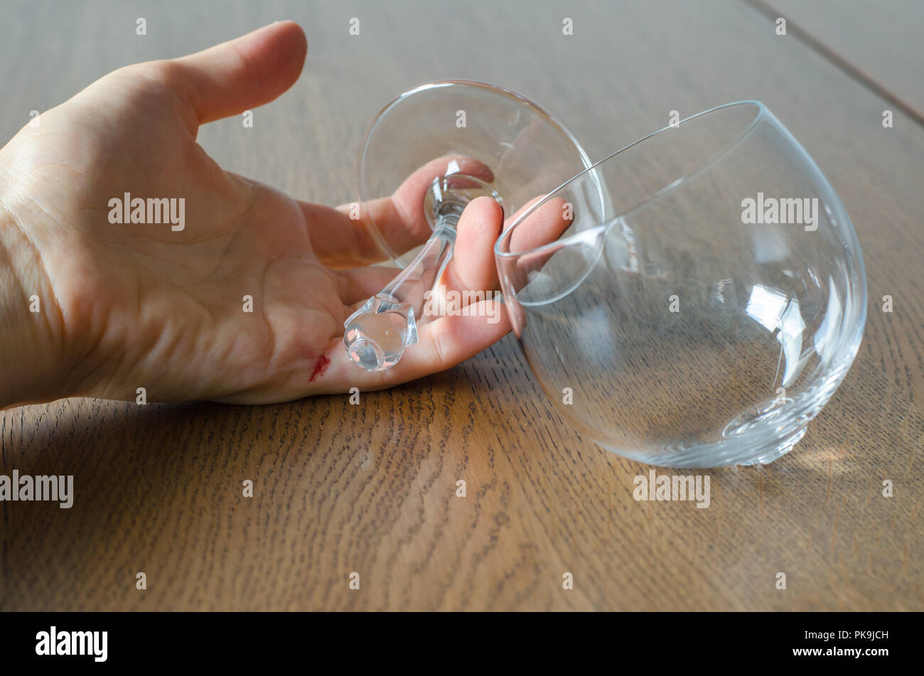 Woman's Hand mit Blut halten gebrochen Wein Glas auf Holz- Hintergrund. Stockfoto