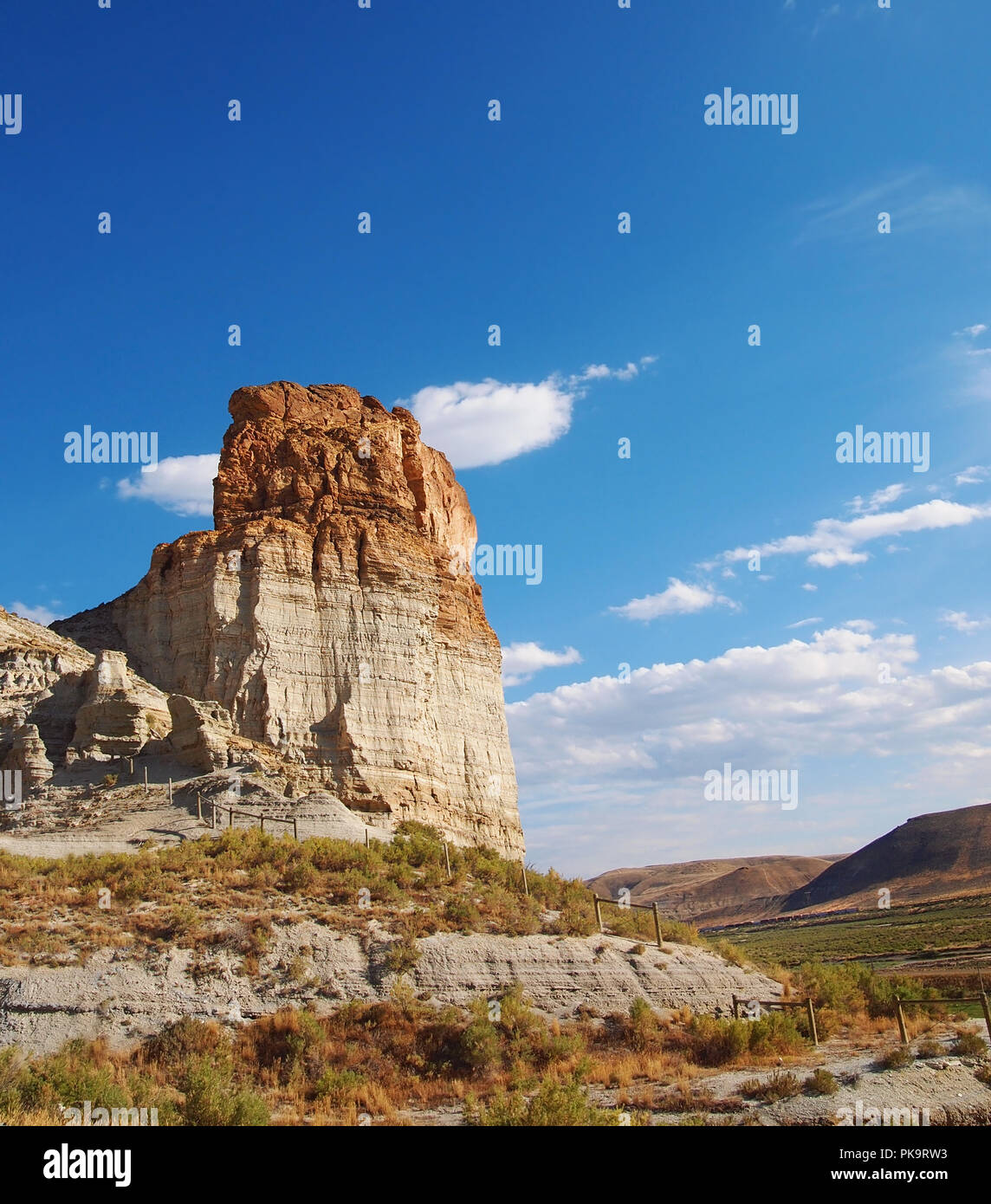 Ein hohes, butte steht über eine Landschaft von sagebrush und erodierten Felsen mit Hügeln im Hintergrund, in den Roten Wüstenregion von Wyoming. Stockfoto