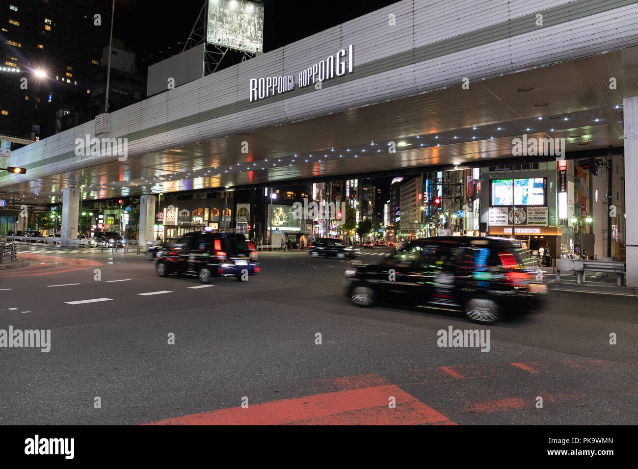 Autos fahren durch Roppongi Bezirk in Tokio bei Nacht. Stockfoto
