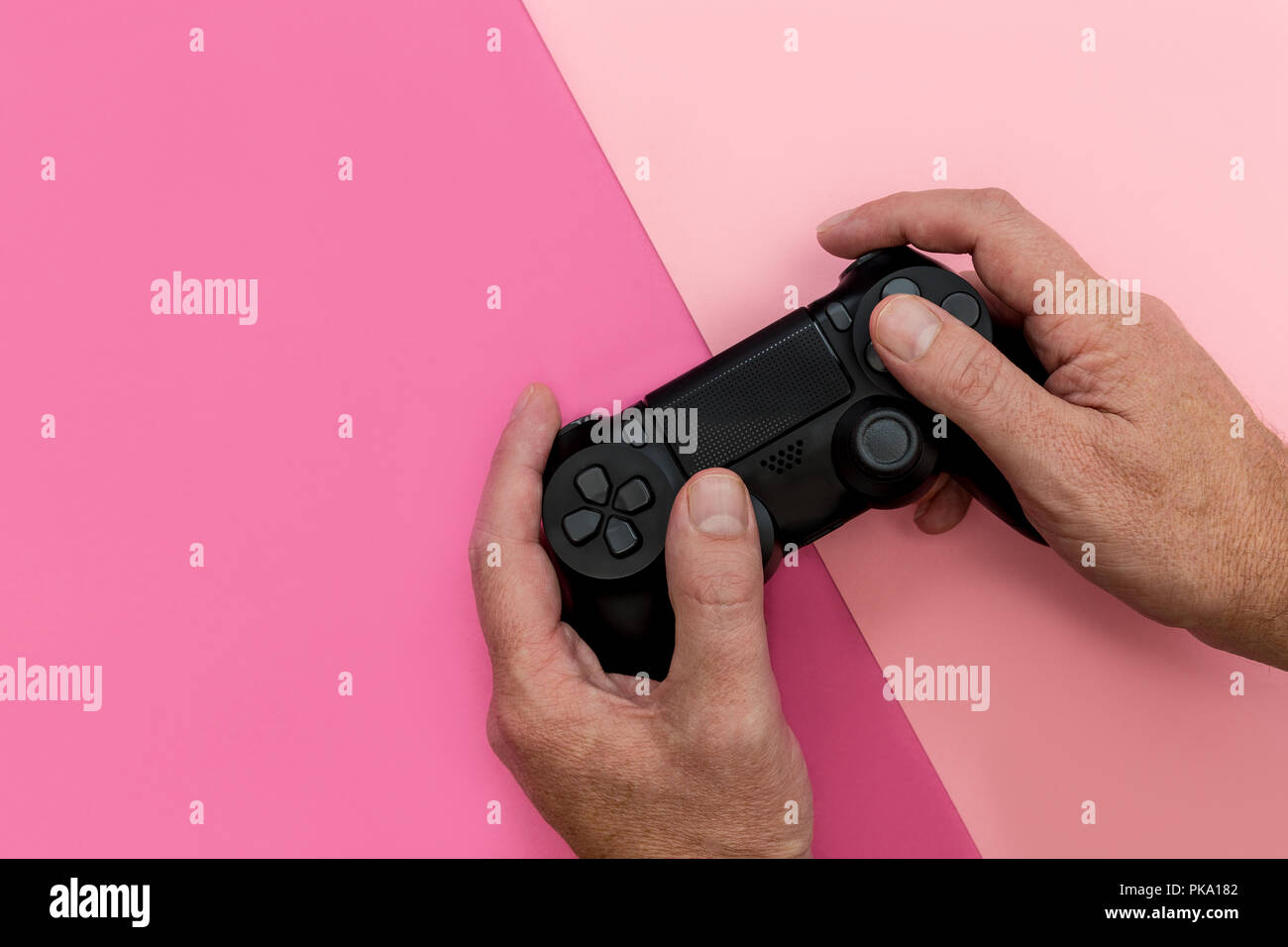 Mann spielt Video Spiel mit Controller auf hellen rosa Hintergrund Stockfoto