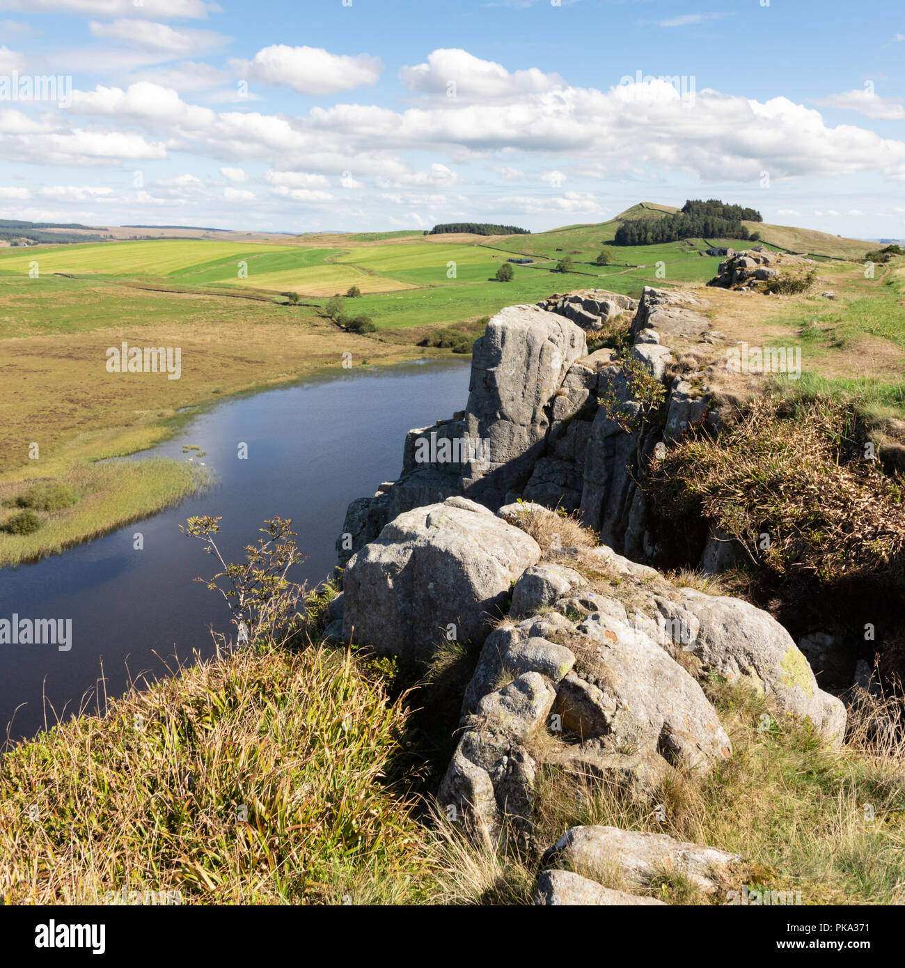 Ein Blick von Oben auf Felsen auf Hadrian's Wall auf der Pennine Way weg. Im Vordergrund stehen die arge Felsen und eine kleine Bäumchen, lehnt sich über einen See. Stockfoto