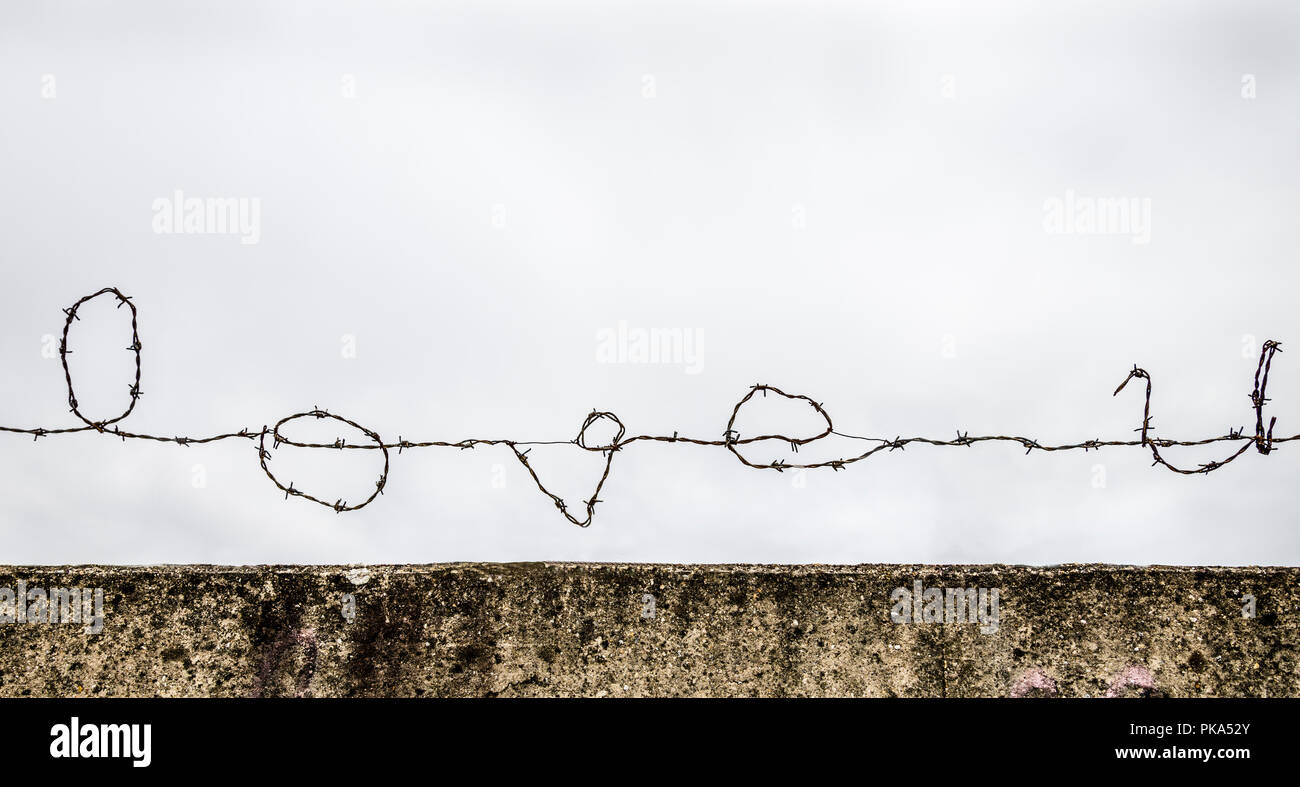'Love u' mit Stacheldraht gegen einen grauen Himmel geschrieben. Stockfoto