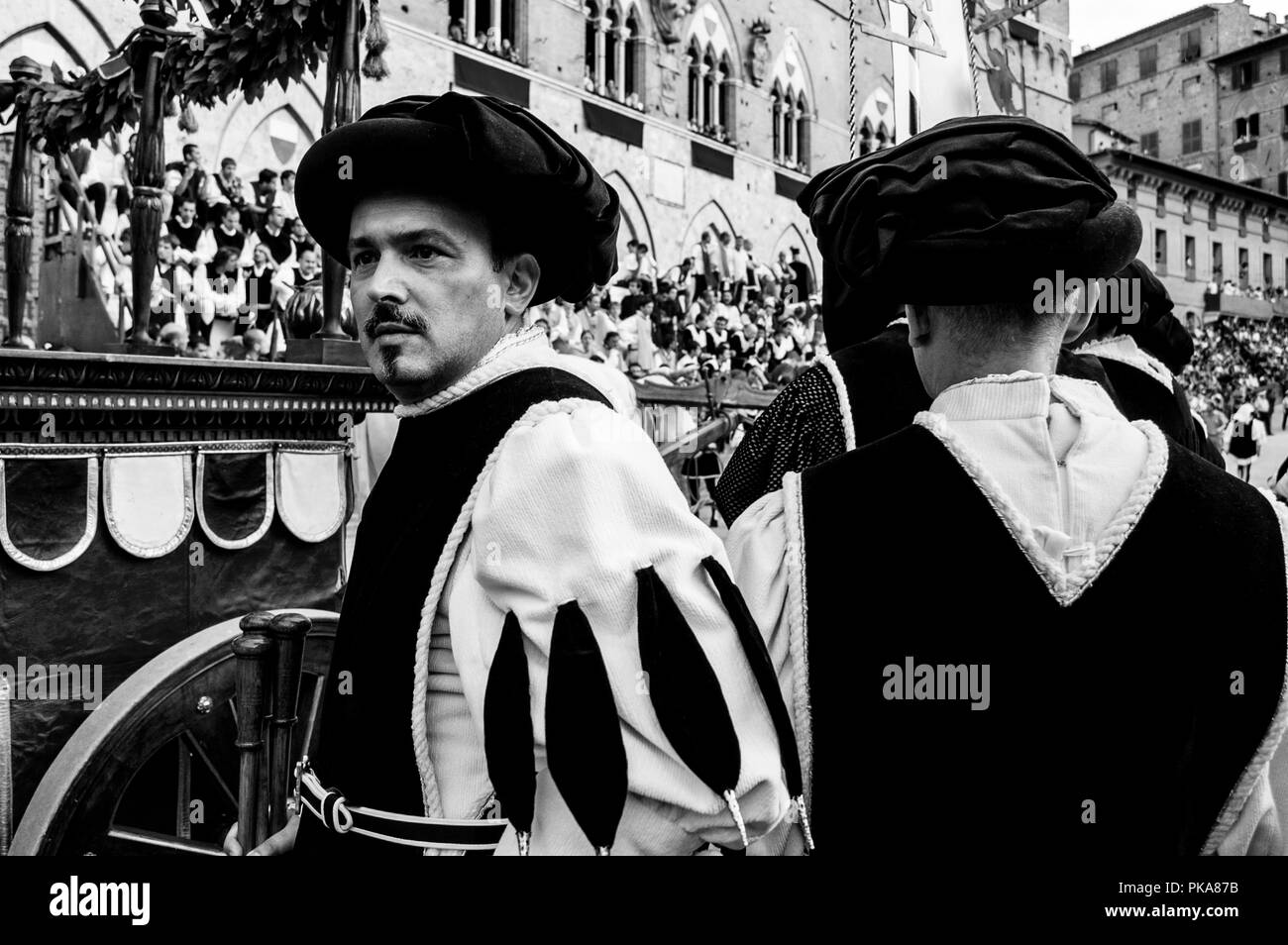 Stewards in Schwarz gekleidet und Weiß Kostüm direkt Die Corteo Storico (Historische Prozession) Auf der Piazza Del Campo, Palio Di Siena, Italien Stockfoto