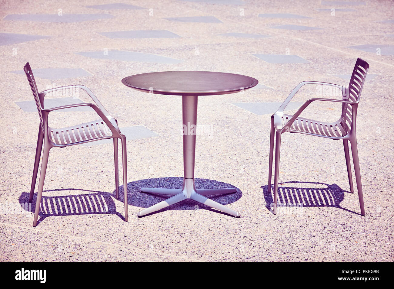 Zwei Stühle durch eine leere Tabelle, Farbe getonte Bild. Stockfoto