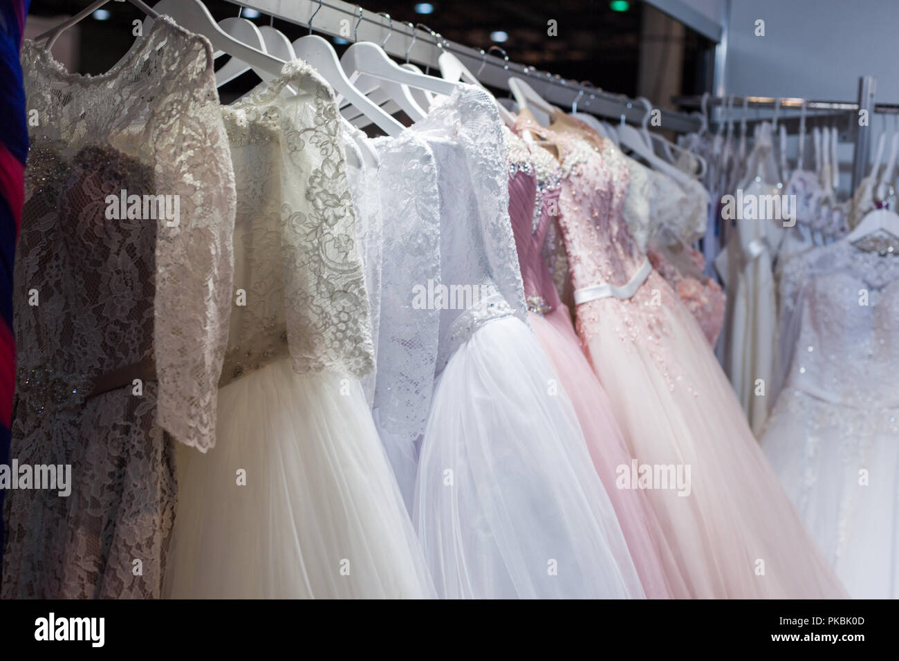 Hochzeits- und Abendkleider hängend an einem Rack im Shop. Stockfoto