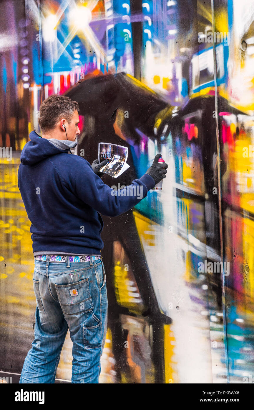 Ein Graffiti Künstler erstellen einer bunten regnerischen Nacht Zeit street scene studieren das Original in Spitalfields, London, England, Großbritannien Stockfoto