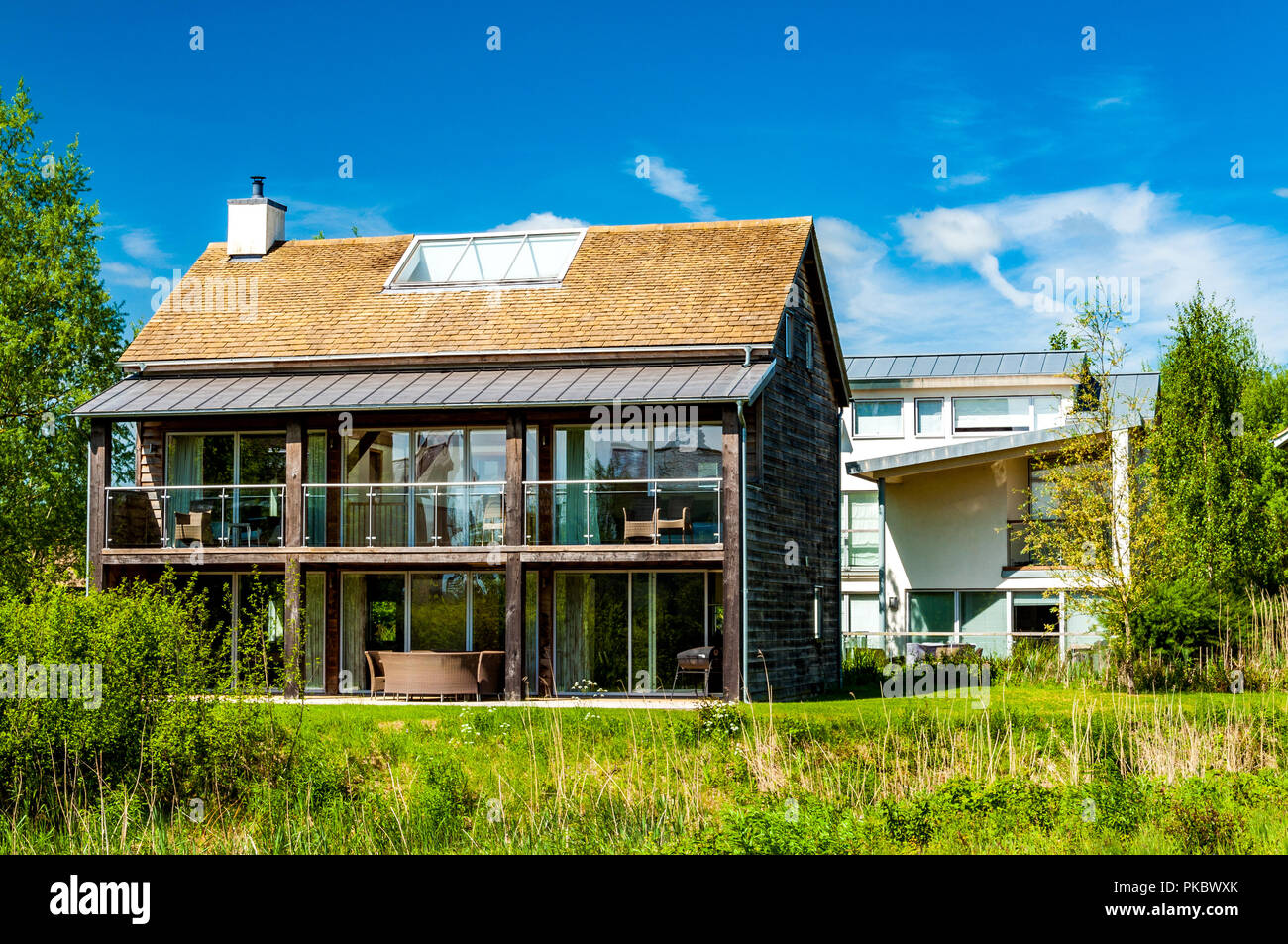 Ein modernes Glas und Holz Haus mit Terrassen und Veranden im Grünland, die Cotswolds, England, Großbritannien Stockfoto