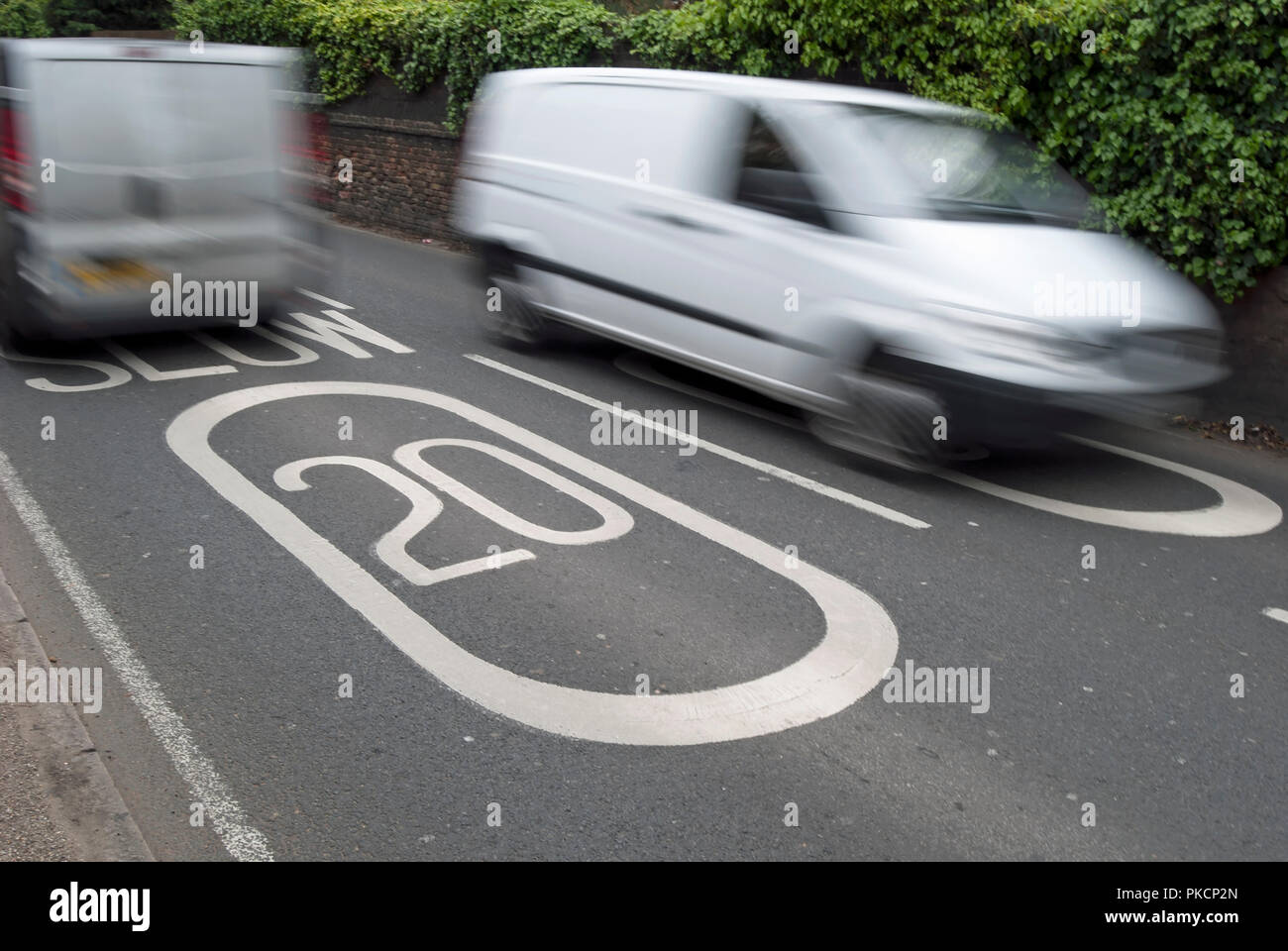 Fahrzeuge gesehen in verschwommene Bewegung pass Fahrbahnmarkierungen beschreibt ein 20 mph Höchstgeschwindigkeit in Ham, Surrey, England Stockfoto