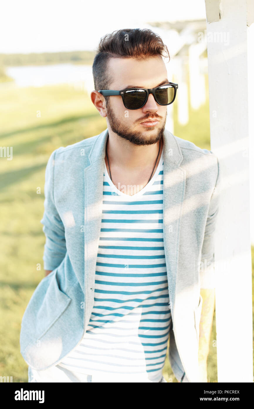 Stattliche hipster Mann in einer Jacke, die in einem Sommer T-Shirt und Sonnenbrille an einem sonnigen Tag. Stockfoto