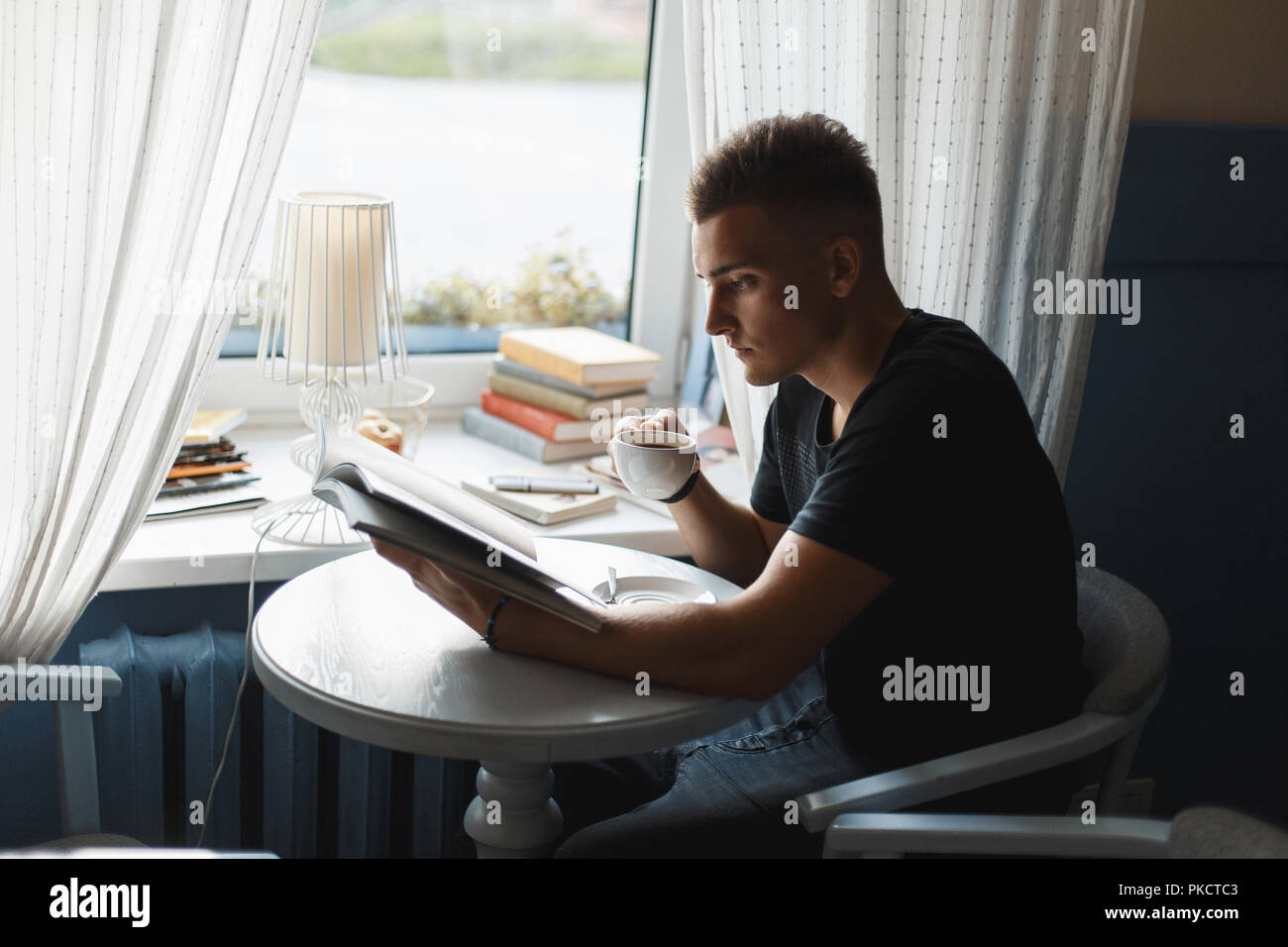 Stattlicher Mann mit Kaffee, ein Buch zu lesen. Stockfoto