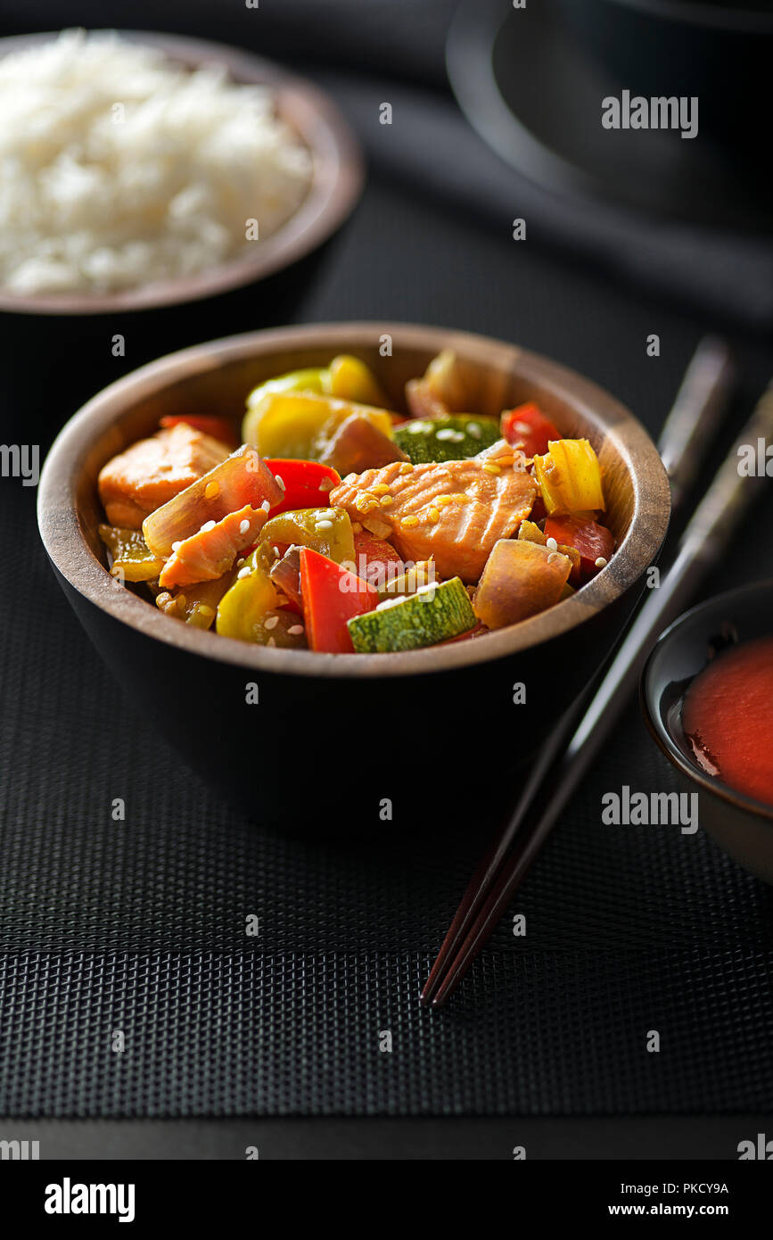 Chinesisches Essen mit Lachs Fleisch und Gemüse auf schwarzem Hintergrund Stockfoto