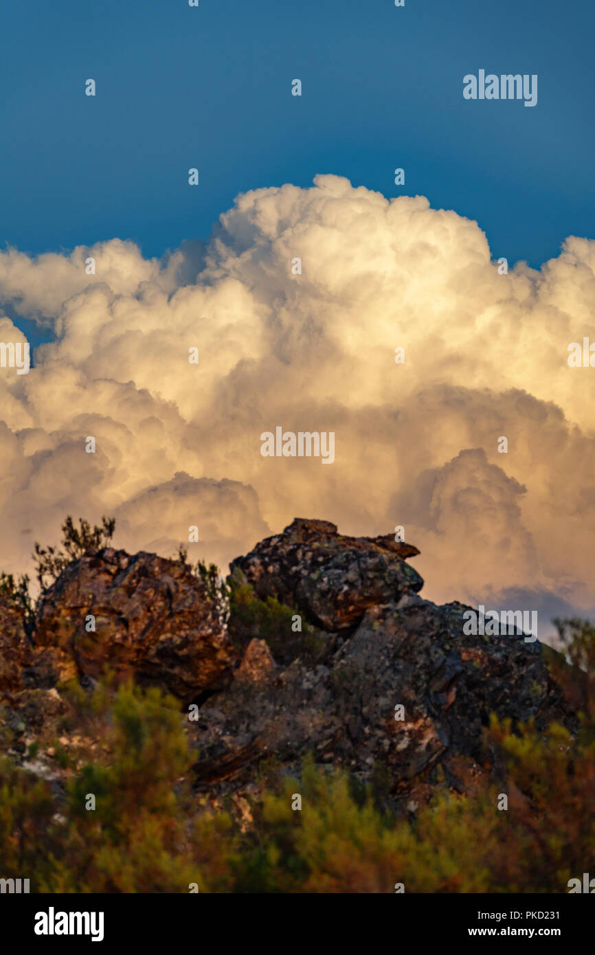Riesige Wolken hinter unscharfer Felsen, blauer Himmel Stockfoto