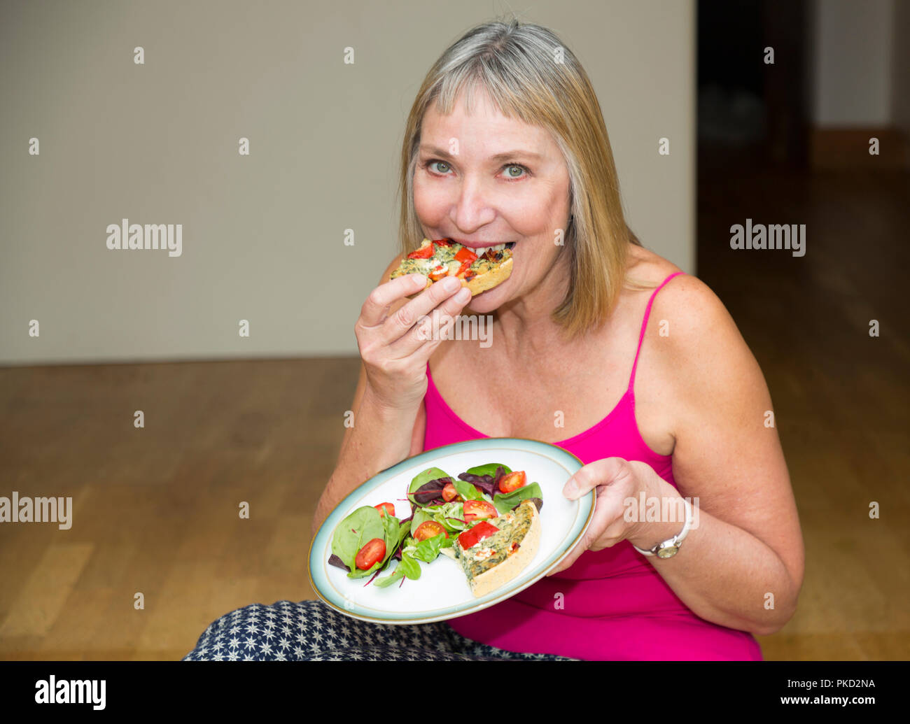 Frau essen eine Quiche und Salatteller Stockfoto
