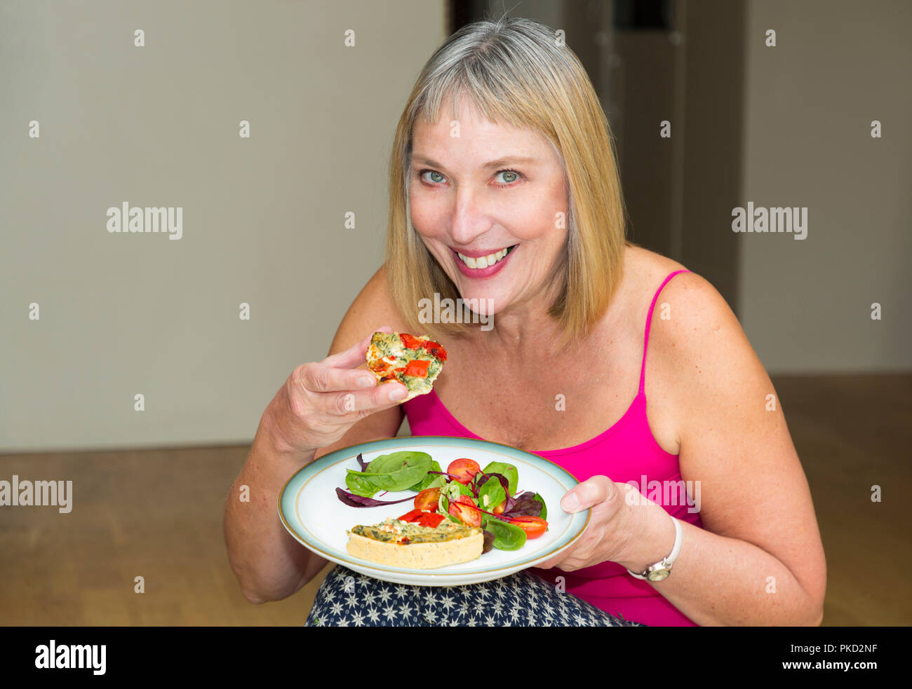 Frau essen eine Quiche und Salatteller Stockfoto