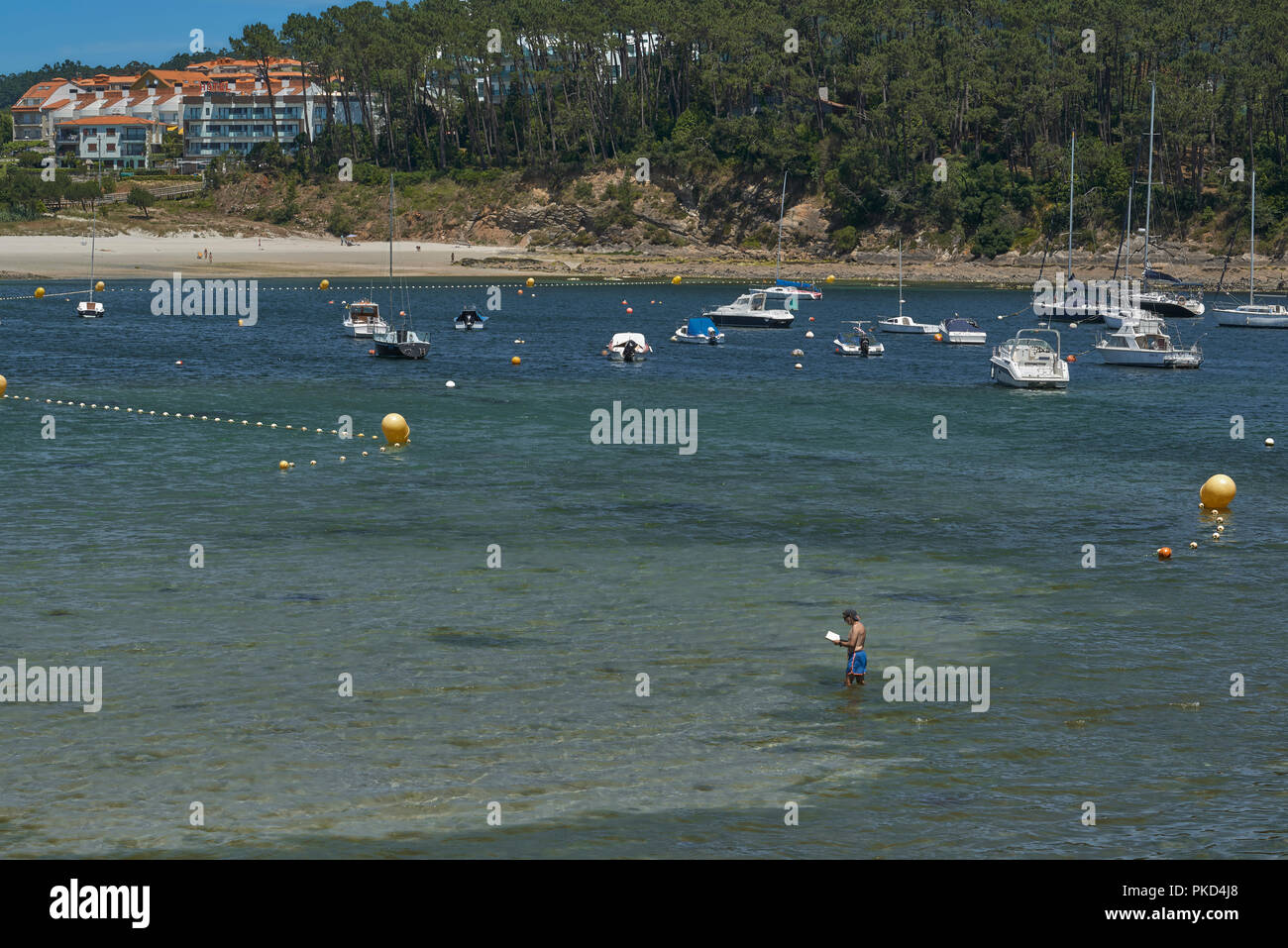 Touristische lesen ein Buch über das Wasser am Strand von Portonovo, Pontevedra, Galizien, Spanien, Europa Stockfoto