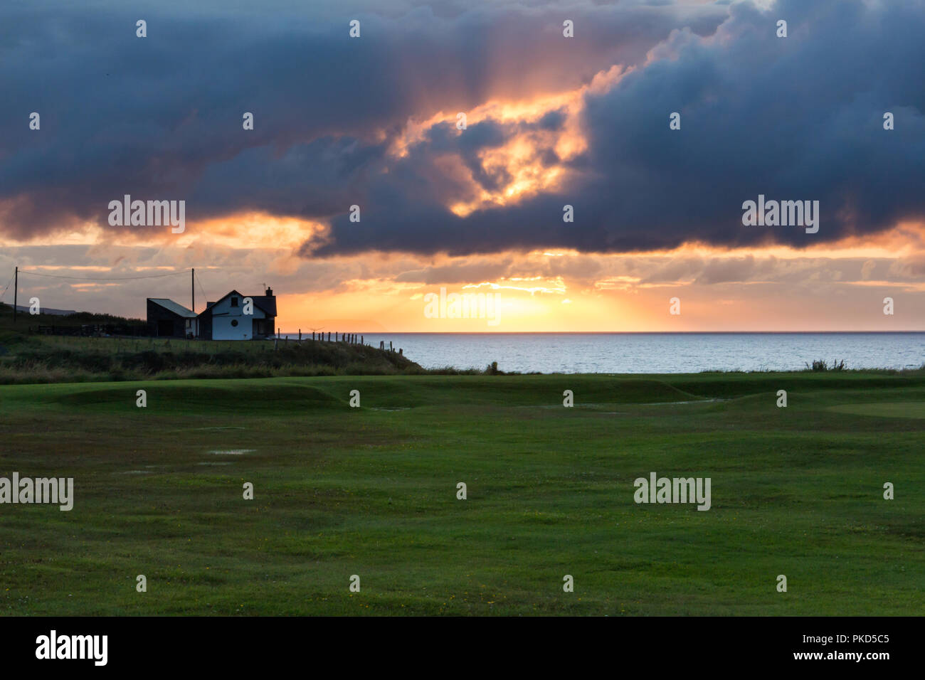 Dramatischer Sonnenuntergang durch dunkle Wolken über der Nord Antrim Coast, Portstewart, N. Irland zu brechen. Stockfoto