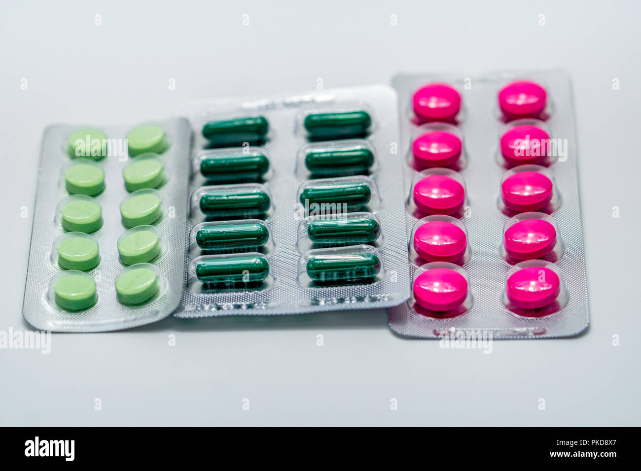 Rosa Filmtabletten und grünen Kapsel und grüne Tabletten im Blister auf weißem Hintergrund. Schmerzmittel Medizin. Pharmazeutische Industrie. Apotheke Apotheke Stockfoto