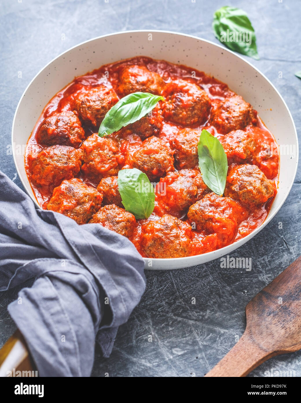 Leckeres Rindfleisch Frikadellen in Tomatensoße mit Gewürzen und frischem Basilikum auf einem Küchentisch. Essen Fotografie, vertikaler, europäische Küche. Stockfoto
