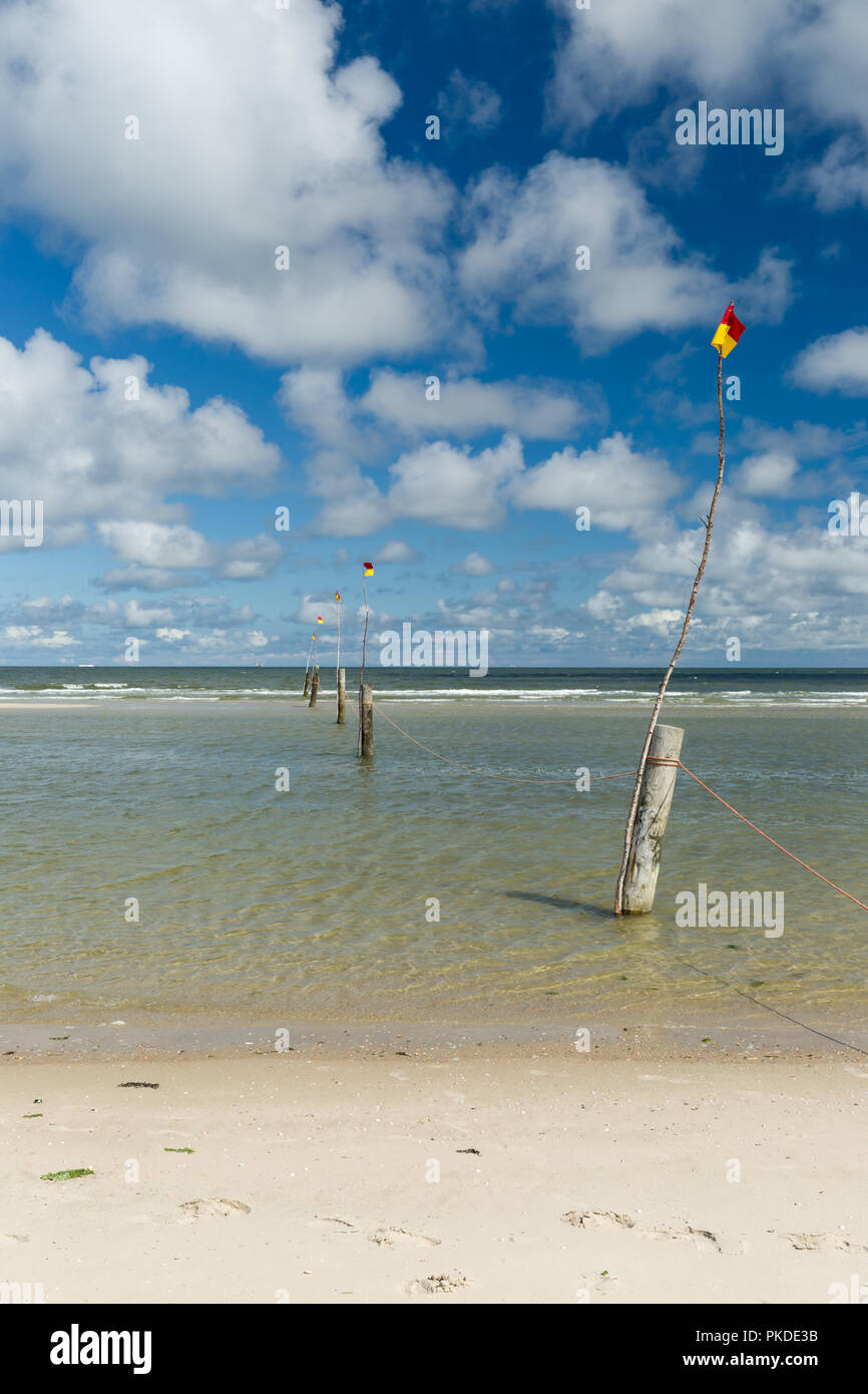 Eine Reihe von Stangen Kennzeichnung der Badebereich in die Nordsee in Norderney führenden mit bewölktem blauen Himmel im Hintergrund. Großem Betrachtungswinkel Stockfoto