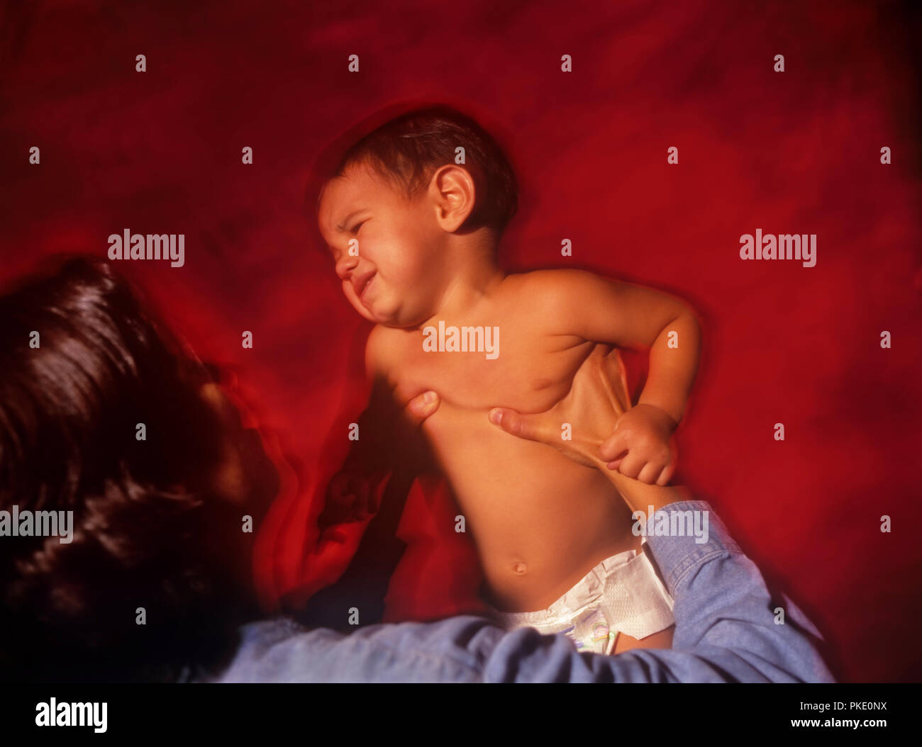 Ein baby boy, indem Sie kräftig von seiner Mutter erschüttert misshandelt. Stockfoto