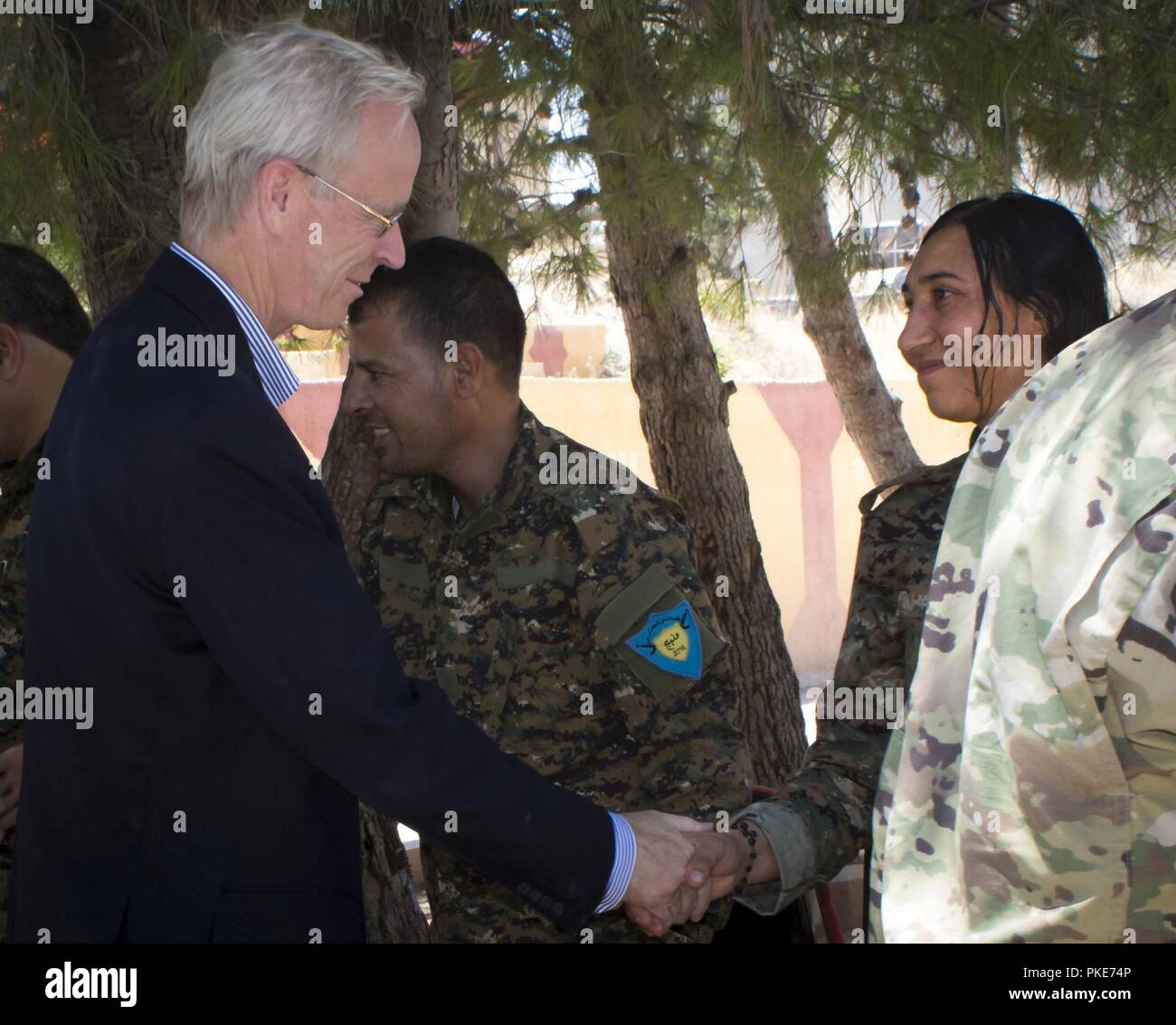 Botschafter William V. Roebuck grüßt ein Mitglied der Manbij militärischen Rat bei seinem jüngsten Besuch in Manbij, Syrien, 26. Juli 2018. Der Botschafter trafen sich mit Mitgliedern der MMC, neben US-Generäle, die Sicherheit und Stabilität in Manbij zu diskutieren. Die Stadt bereitet sich im zweiten Jahr der Befreiung nach der Niederlage von ISIS zu feiern. Stockfoto