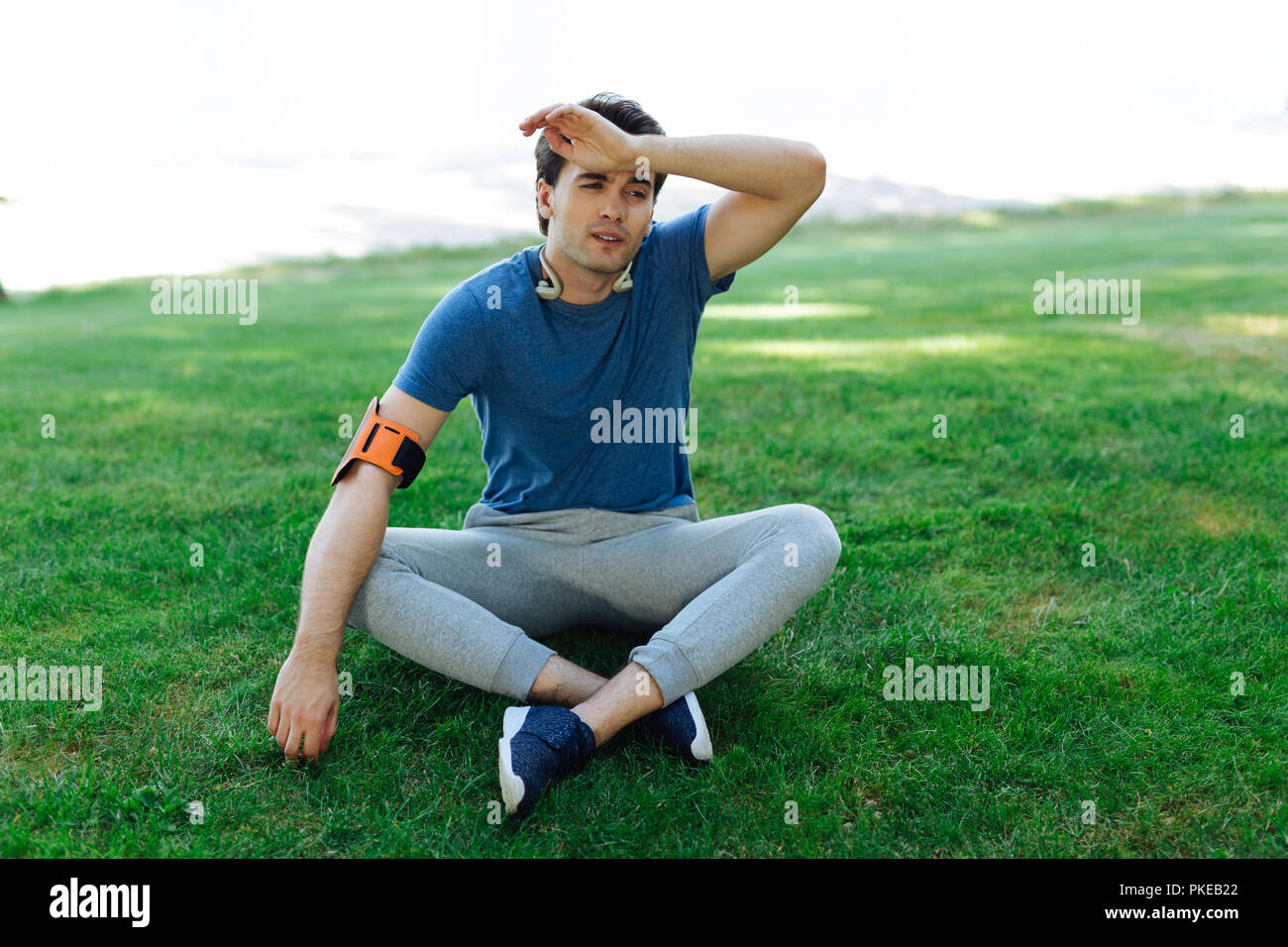 Schön müde Mann sitzt auf dem grünen Gras Stockfoto