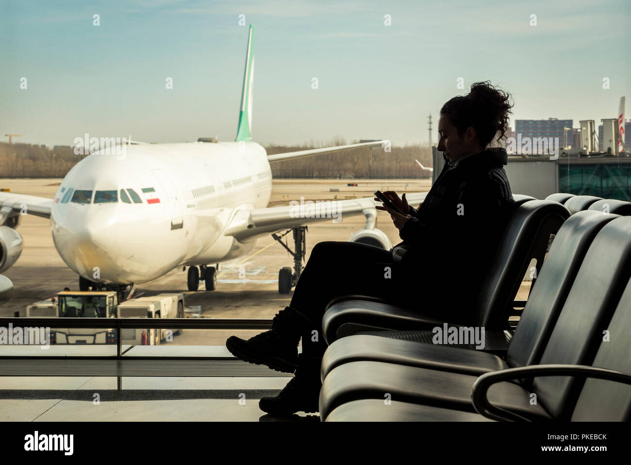 Passagier im Terminal Sitzung mit Ihrem Smart Phone, Beijing Capital International Airport; Peking, China Stockfoto