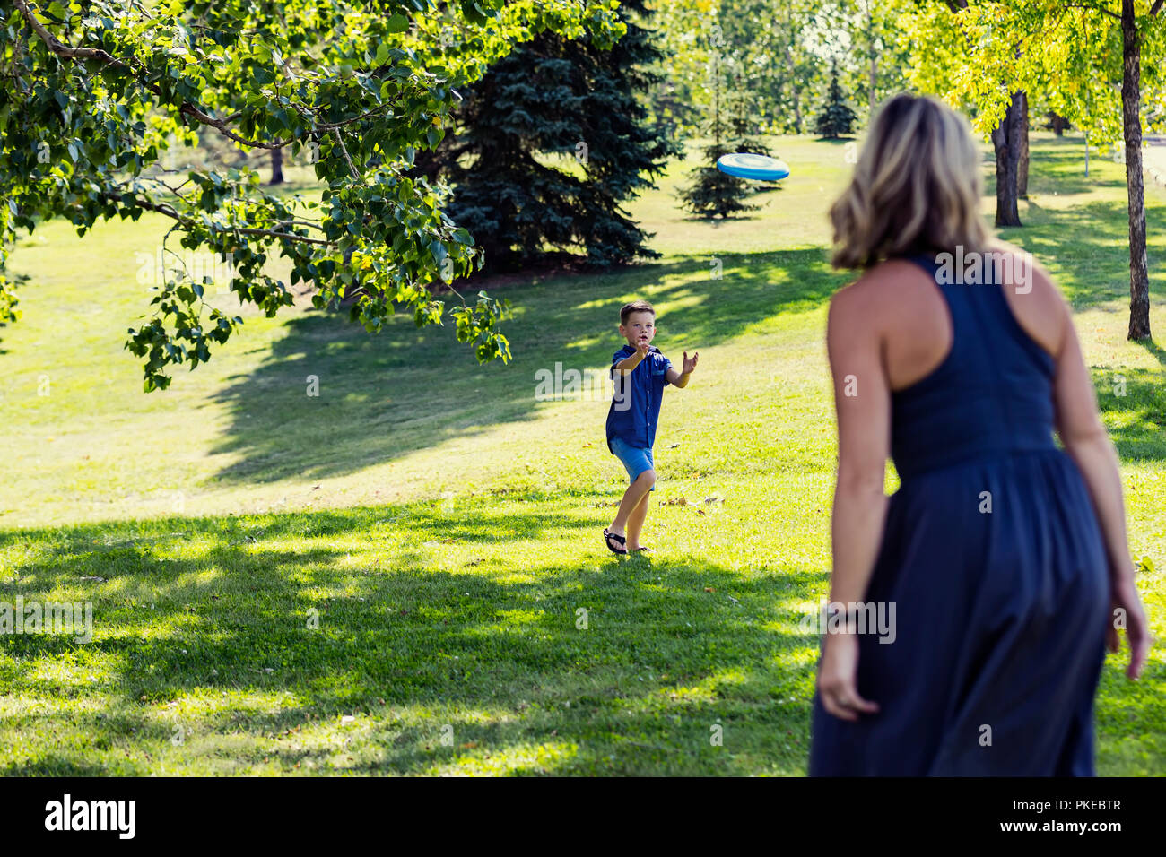 Eine Mutter Werfen einer Disc Spielzeug zu ihrem Sohn in einem Park auf warmen Herbst am Nachmittag bei einem Familienausflug verfangen; Edmonton, Alberta, Kanada Stockfoto