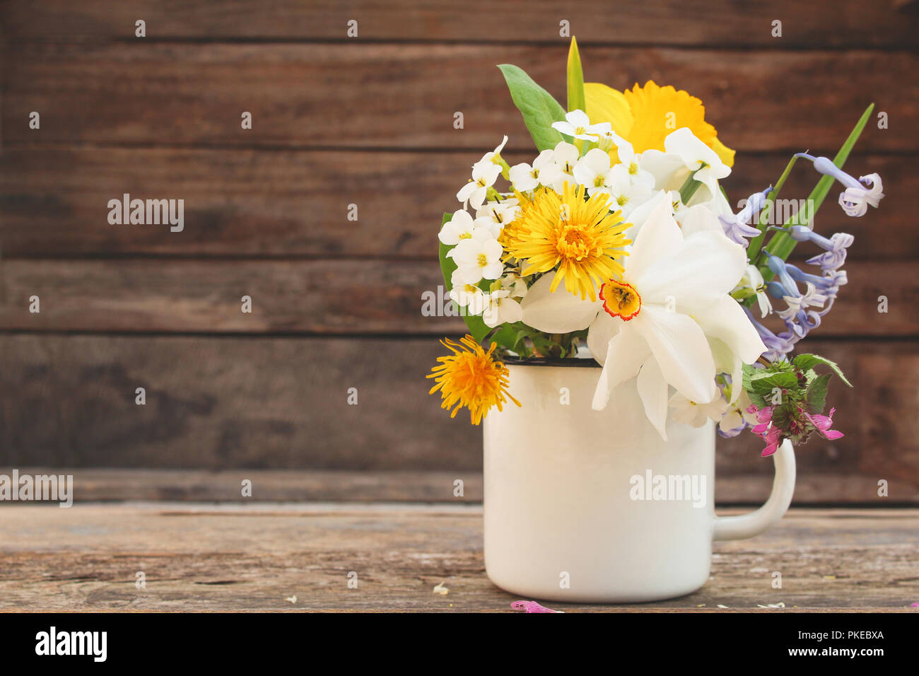 Blumen in einem eisen Becher auf der hölzernen Hintergrund. Getönten Bild. Stockfoto