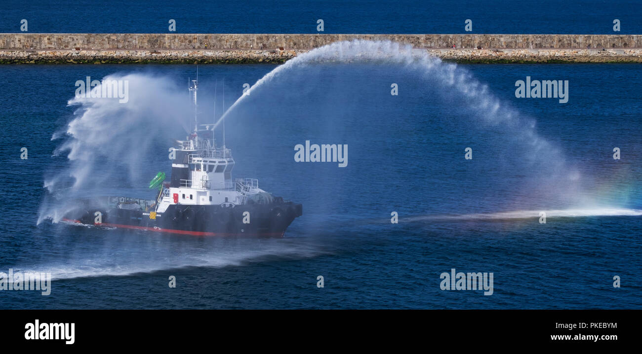 Feuerlöschboot spritzwassergeschützt und erstellen einen Regenbogen in das Meer; La Coruna, Galicien, Spanien Stockfoto