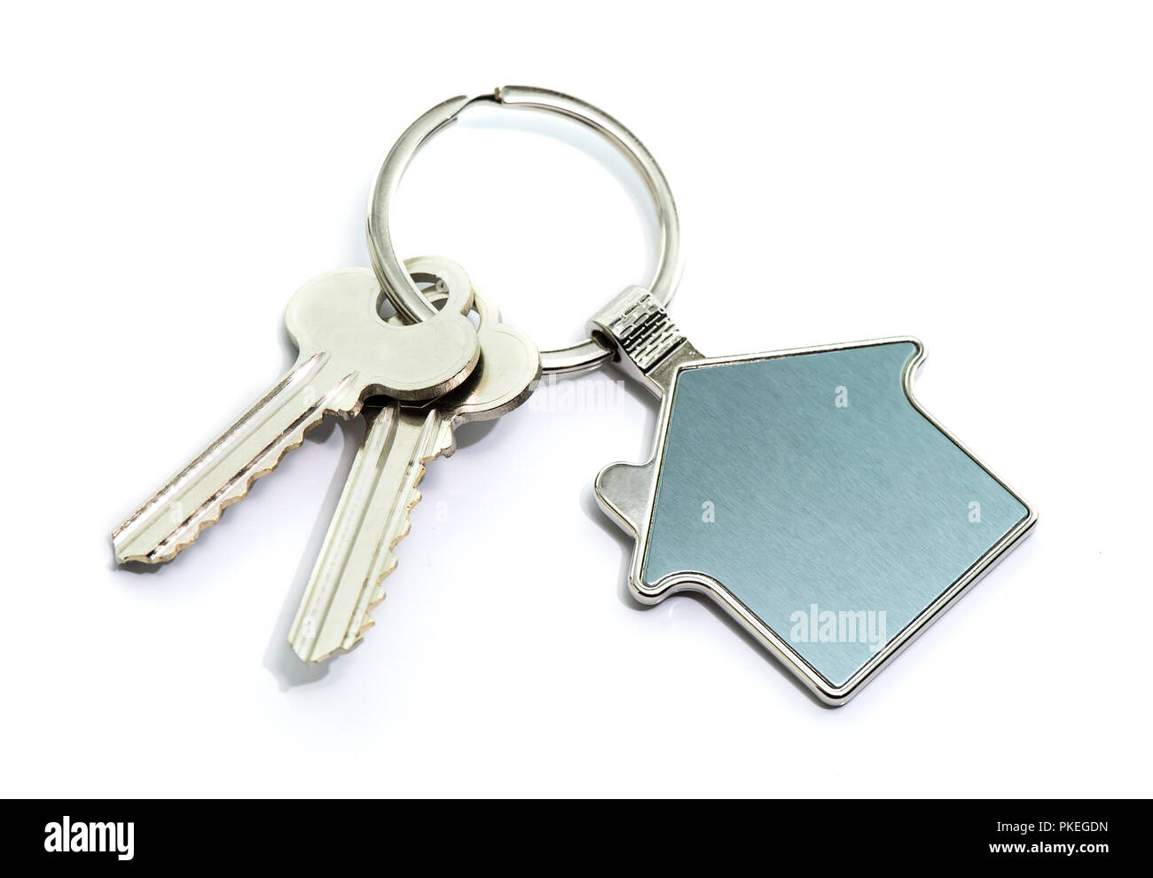 Schlüssel und Schlüsselanhänger in Form von einem Haus auf weißem Hintergrund. Stockfoto