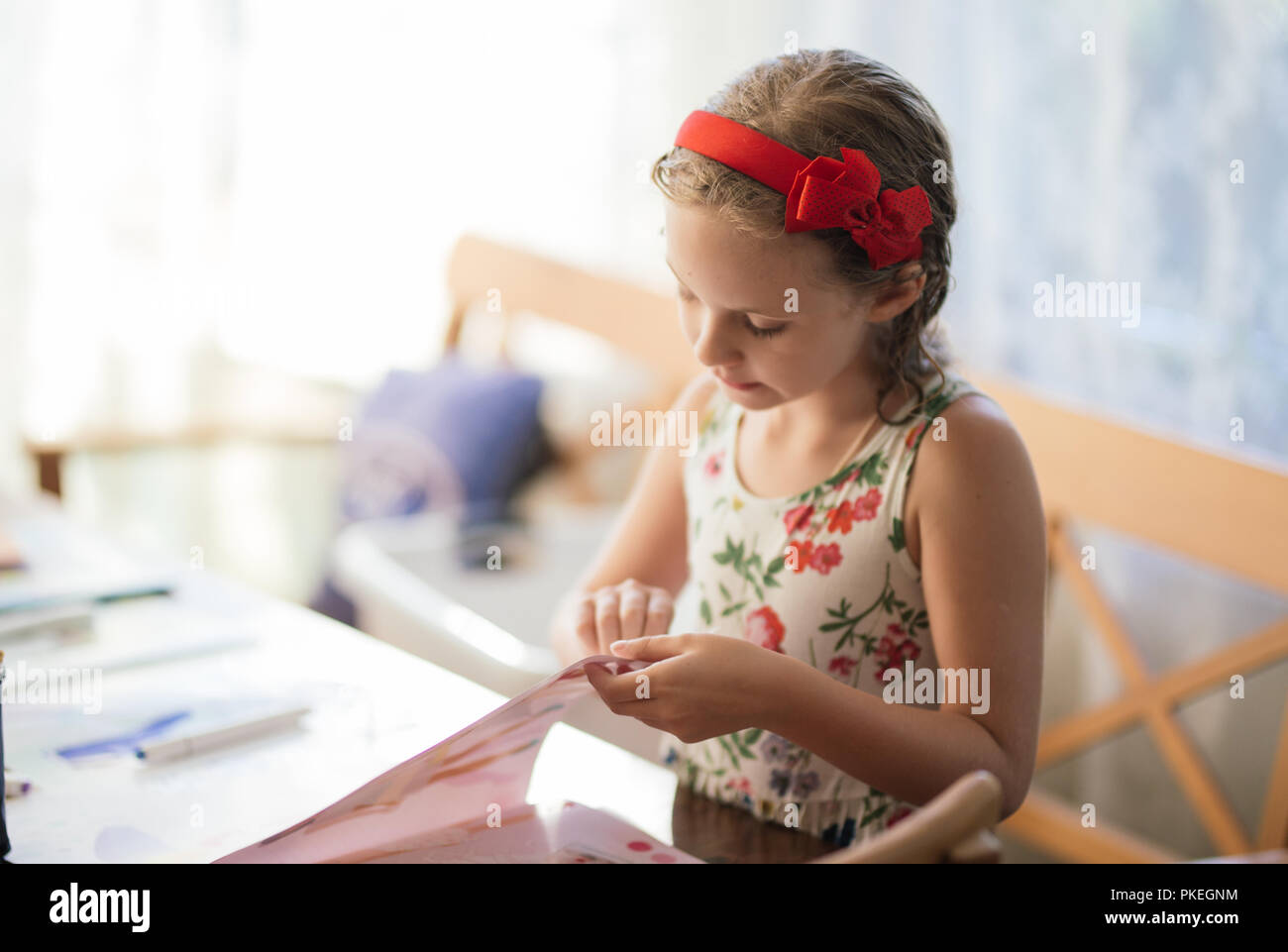 Eine charmante siebenjähriges Mädchen schafft Begeisterung Papier basteln. Hobbys und Interessen. Stockfoto