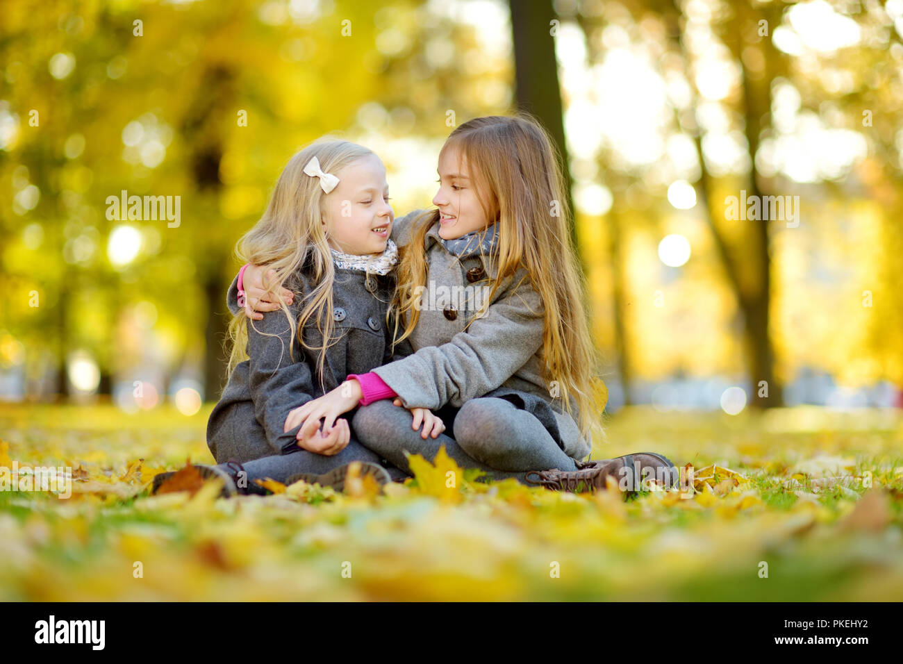 Zwei süße kleine Mädchen Spaß haben auf der wunderschönen Herbsttag. Glückliche Kinder spielen im Herbst Park. Kinder sammeln Gelb Herbst Laub. Herbst Aktivitäten Stockfoto