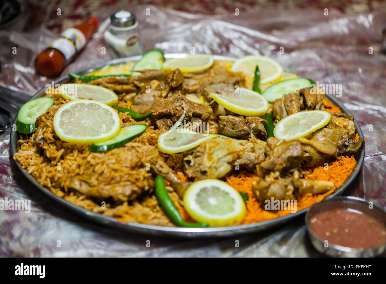 Lamm Salona und Huhn Mandi serviert auf dem Boden in einem Emiratischen Restaurant in Dubai, Vereinigte Arabische Emirate Stockfoto