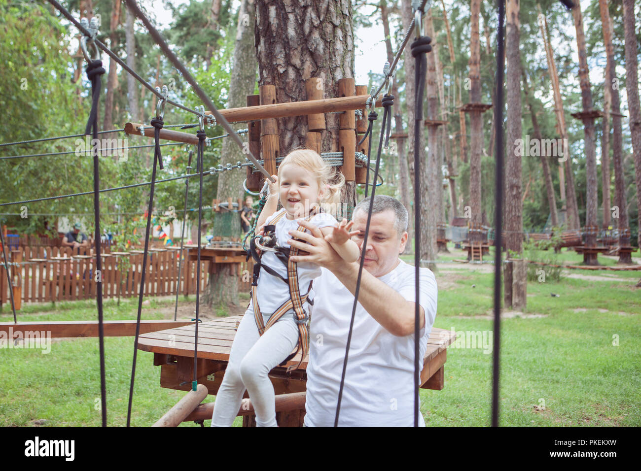 Vater helfen, seine kleine Tochter ein Hindernis im Seilpark zu überwinden. Stockfoto