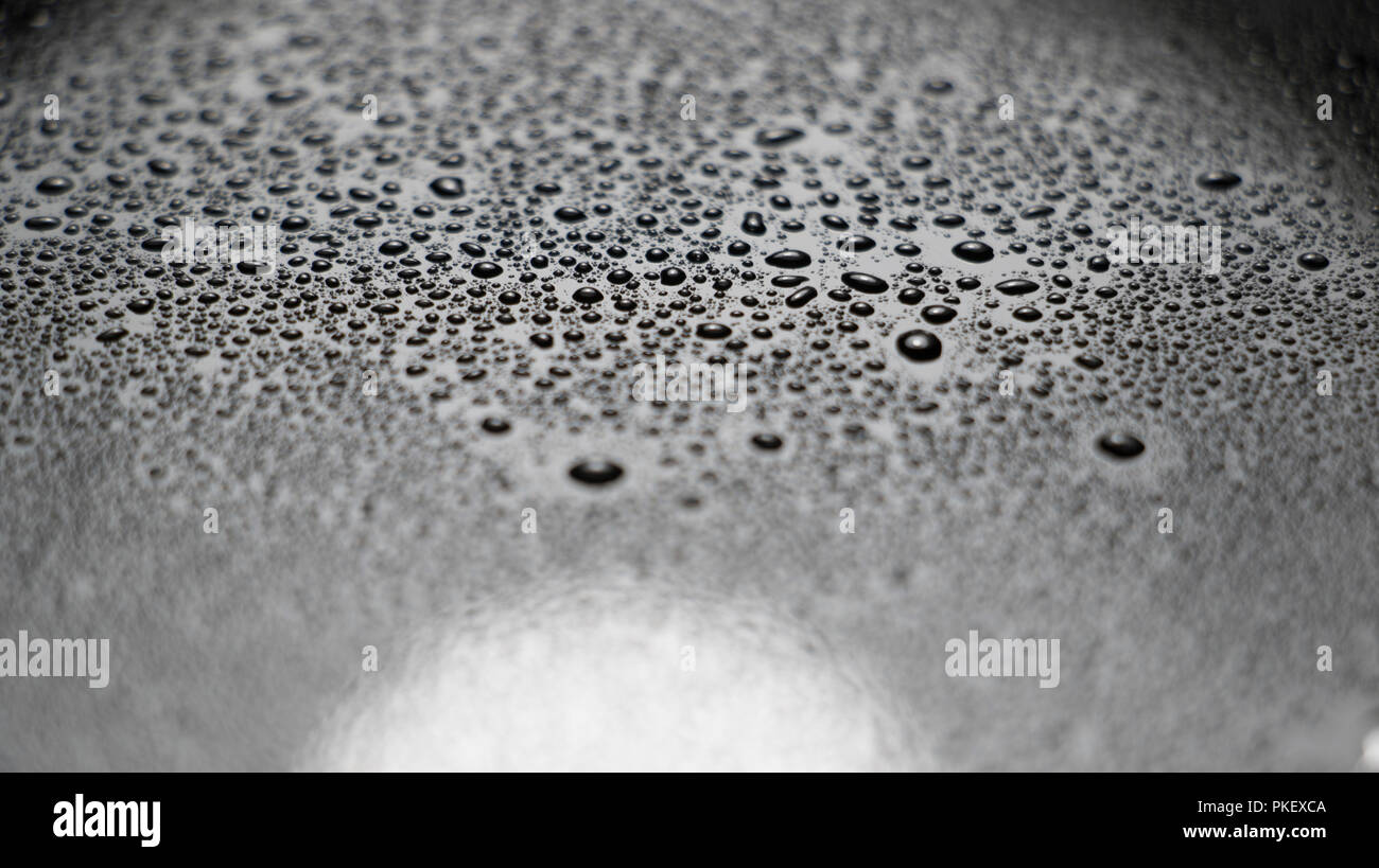 Nahaufnahme von Wassertropfen auf einem glänzenden, glatten Oberfläche. Verschiedene Größen von Wasser perlen. Stockfoto