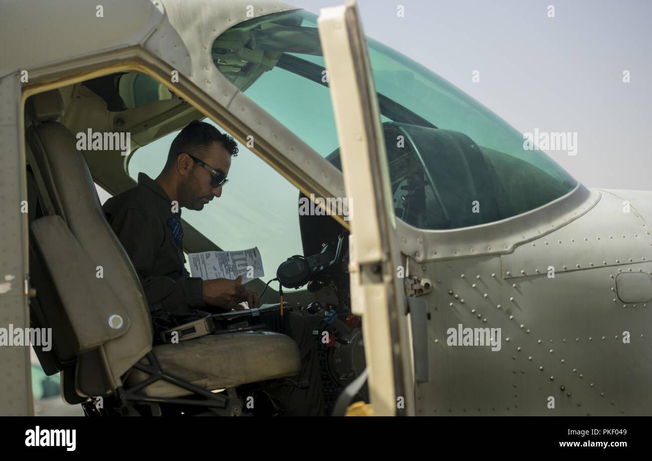 KABUL, Afghanistan (Juli 23, 2018) - ein afghanischer Air Force Pilot einer Cessna 208B auf die 1 Flügel afghanischen Luftwaffe an Hamid Karzai International Airport (Hkia), Afghanistan, organisiert zugeordnet und geht über Dokumente, die für die Ausbildung Flug am 23. Juli 2018. Die Mission Der TAAC - die Luft wird zum Zug, beraten und afghanischen Partner unterstützen eine Professionelle, leistungsfähige und nachhaltige Afghanischen Luftwaffe zu entwickeln. Stockfoto
